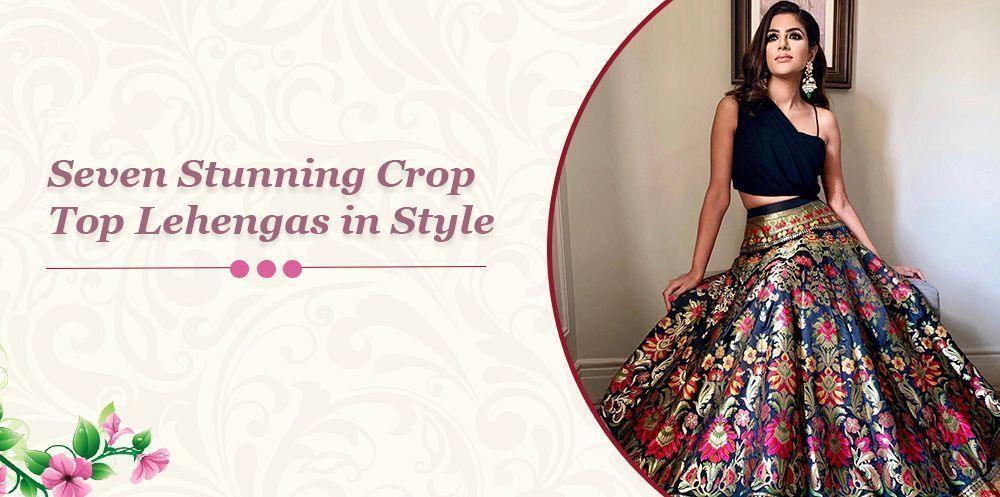 Woman wearing a black crop top lehenga with vibrant floral embroidery, sitting indoors