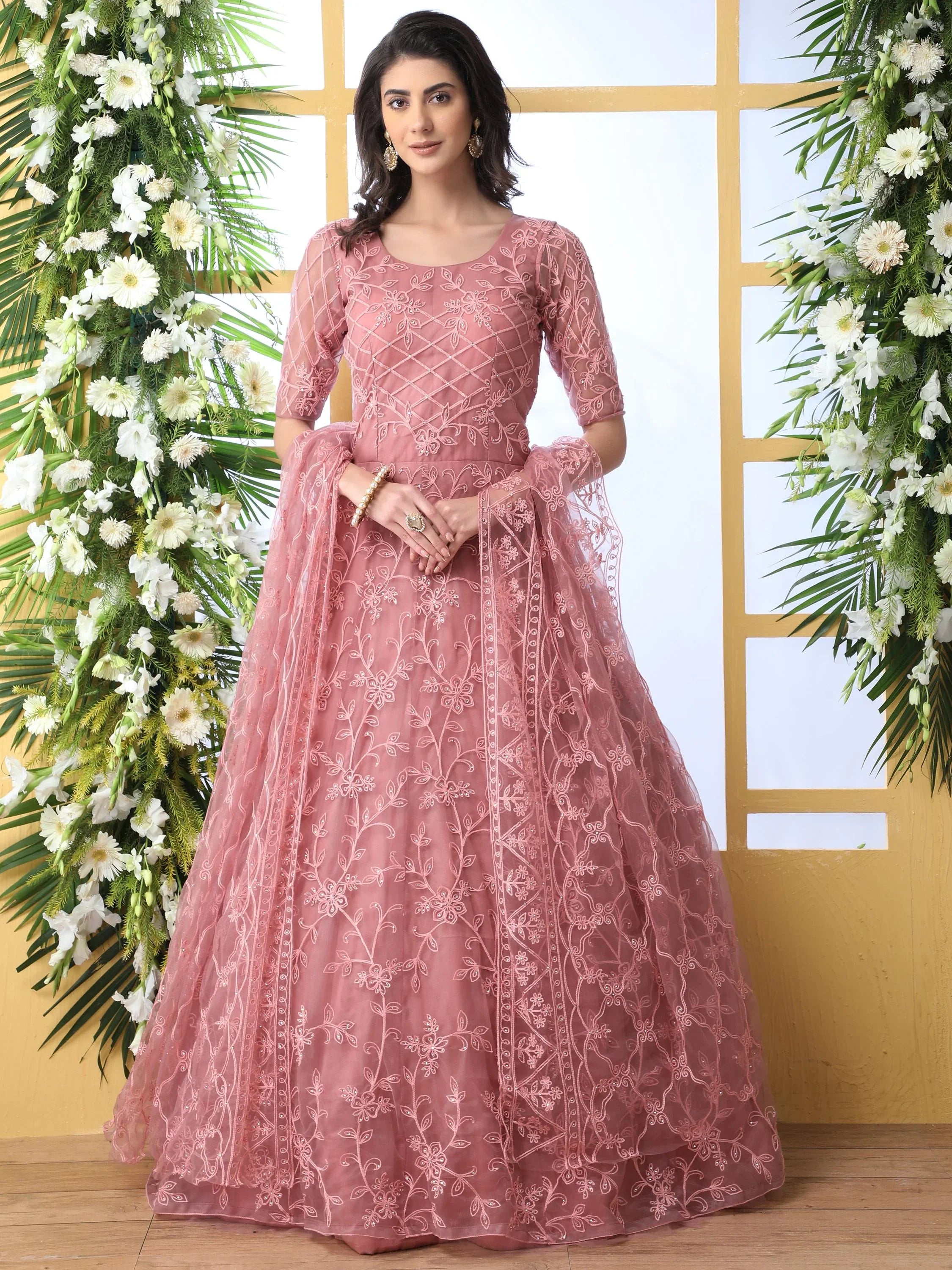 Woman wearing a pink embroidered Indian ethnic gown, ideal for engagement or special occasions