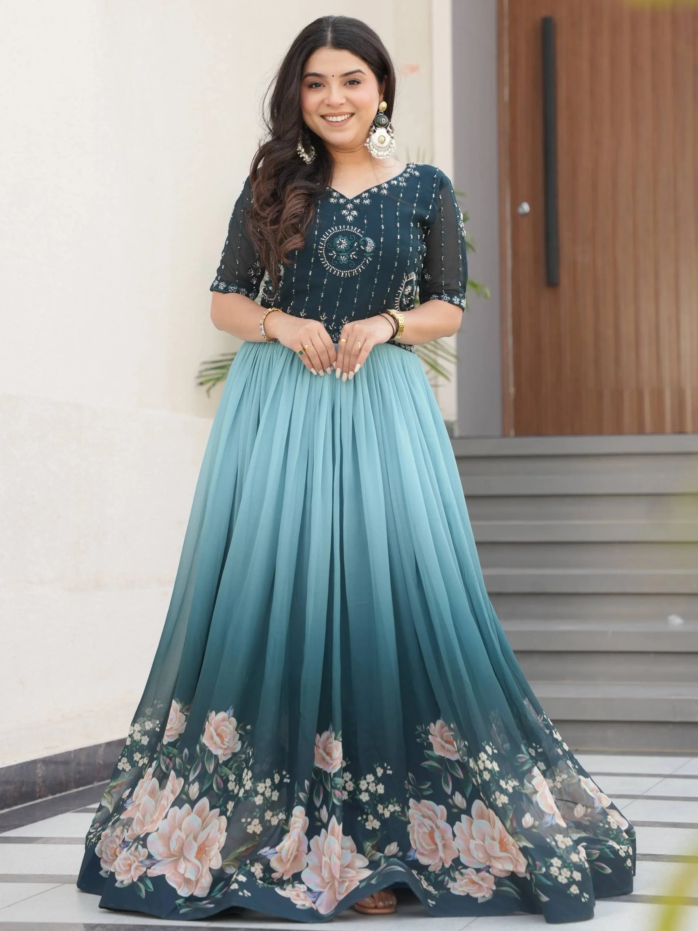 Woman in blue ethnic engagement gown with floral print and intricate embroidery, standing outdoors