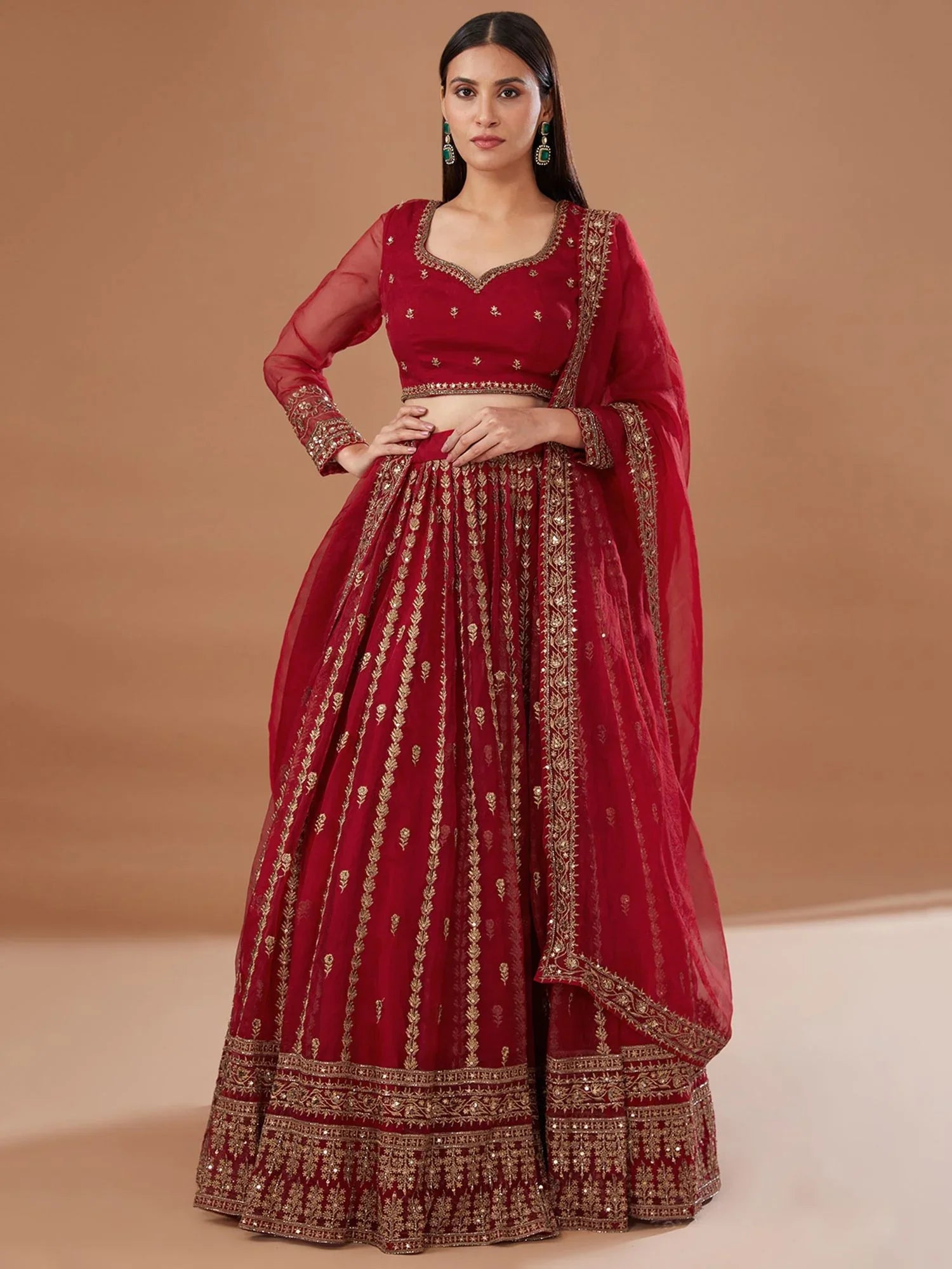 Woman wearing red organza bridal lehenga choli with gold embroidery and sheer dupatta