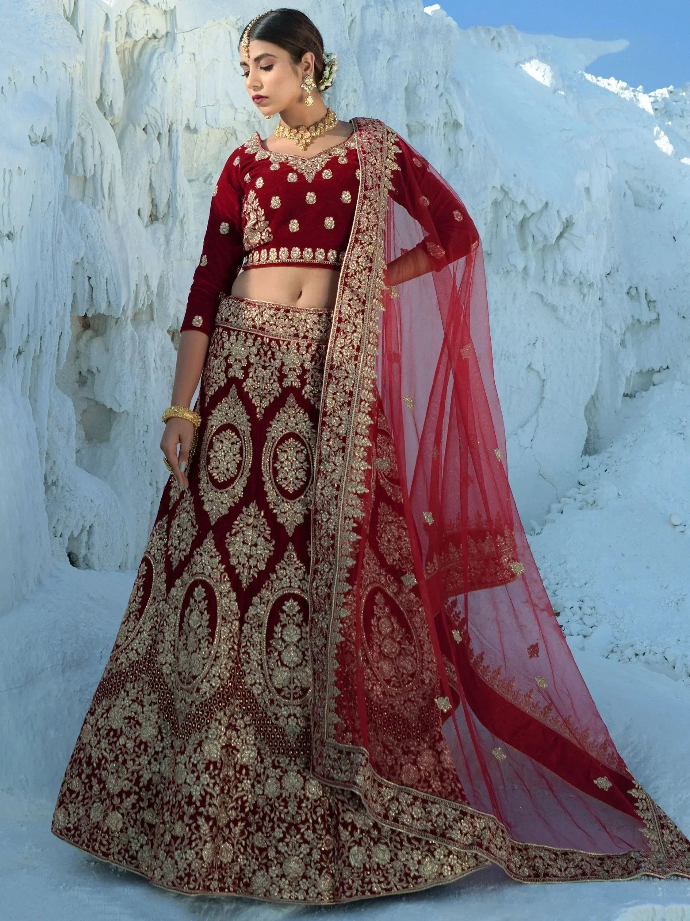 Maroon velvet lehenga choli with gold embroidery, perfect for Indian weddings and festive occasions.