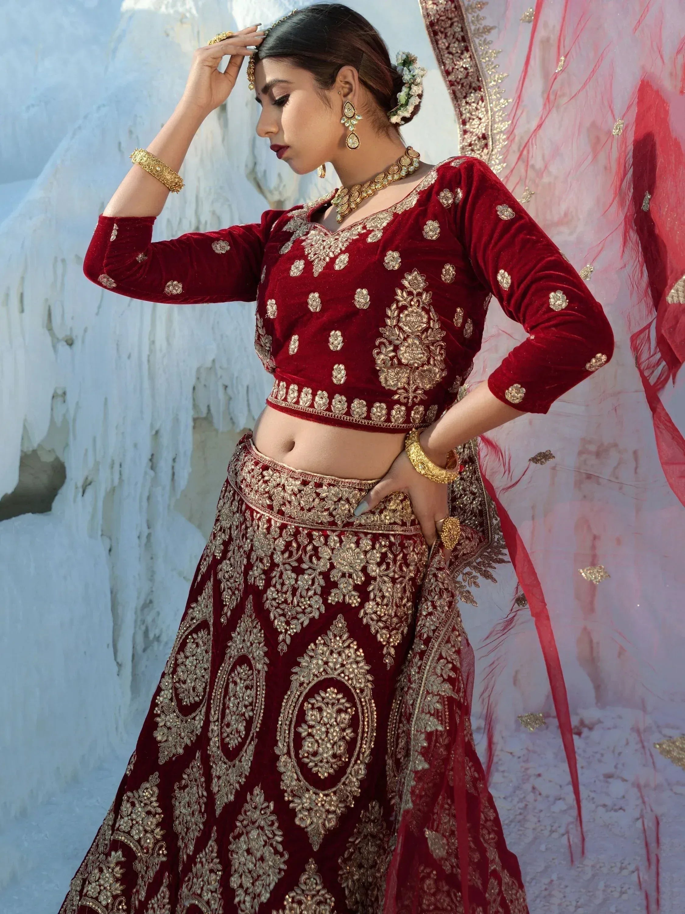 Red velvet lehenga choli with gold embroidery, perfect for Indian weddings and festive occasions.