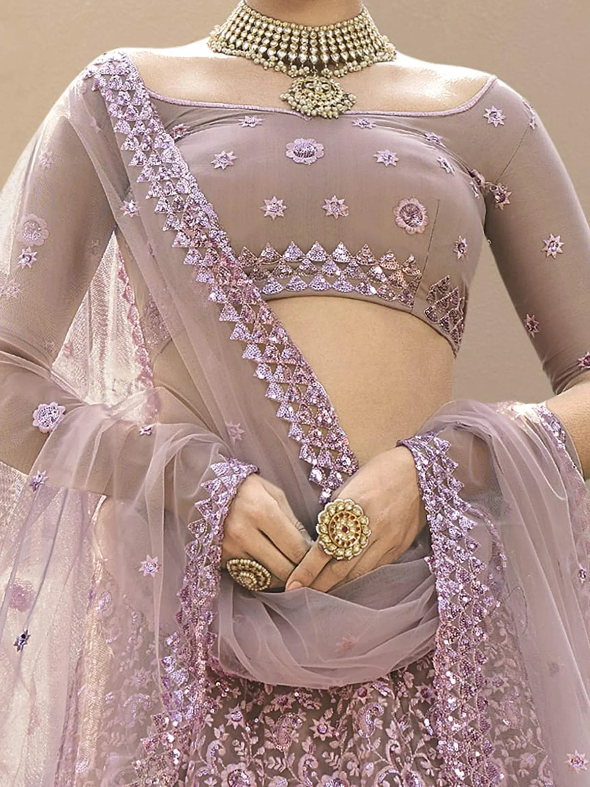 Elegant lavender designer lehenga choli with intricate floral embroidery and sequin detailing, paired with traditional jewelry.