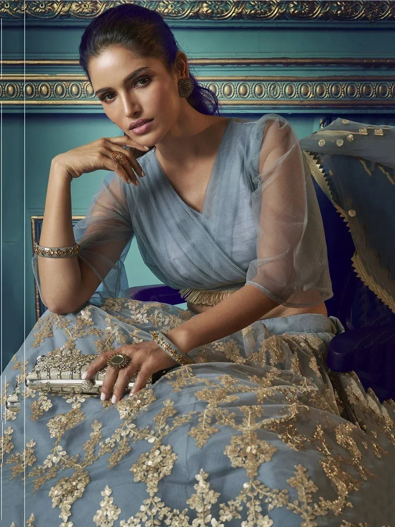 Elegant blue lehenga choli with gold embroidery, sheer sleeves, and traditional Indian jewelry for festive occasions
