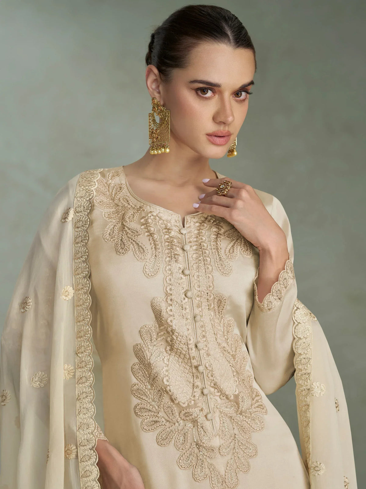 Elegant beige embroidered kurta with floral detailing, paired with matching dupatta and gold jewelry.
