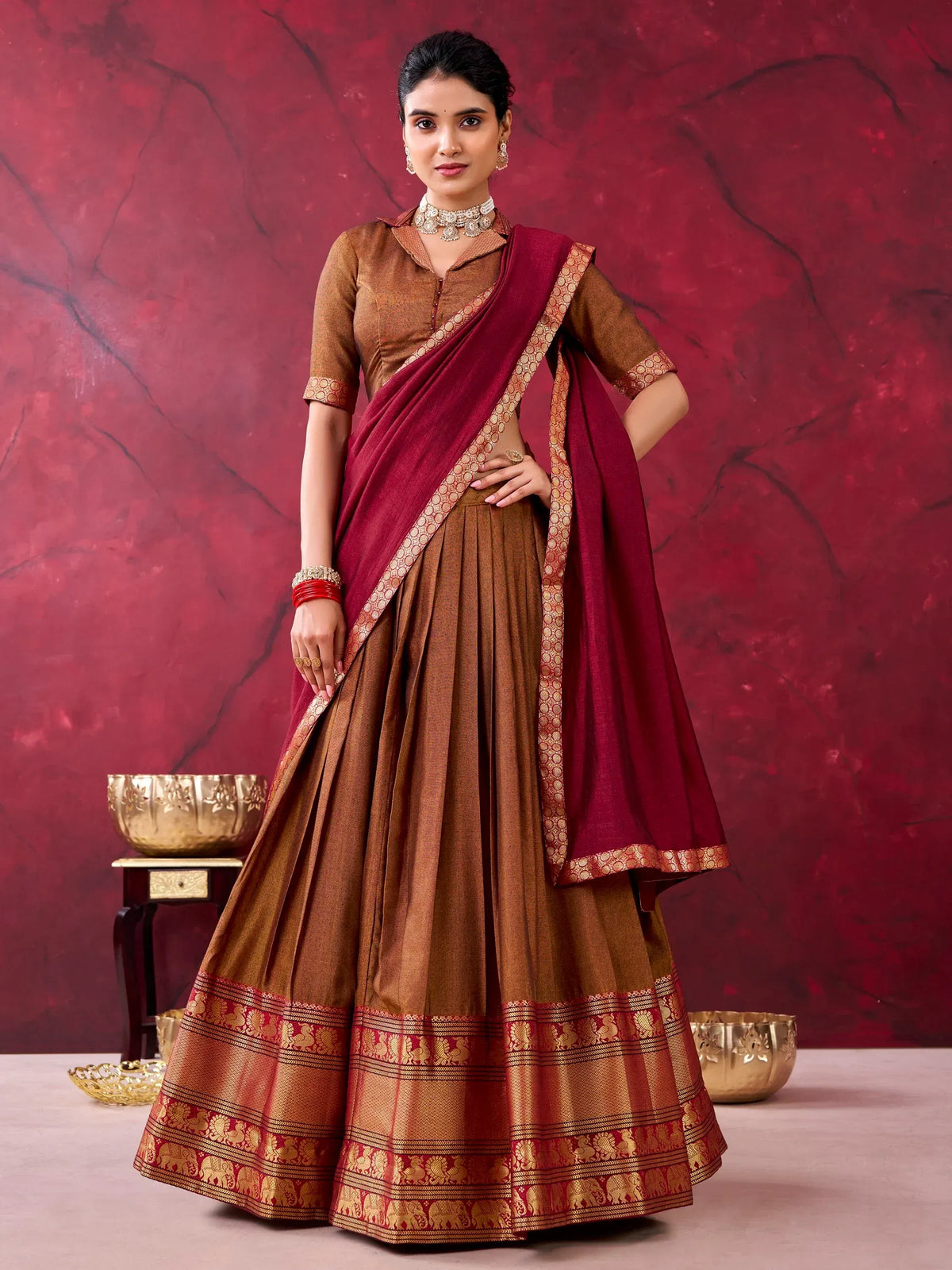 Woman in brown designer lehenga choli with a maroon dupatta and golden border