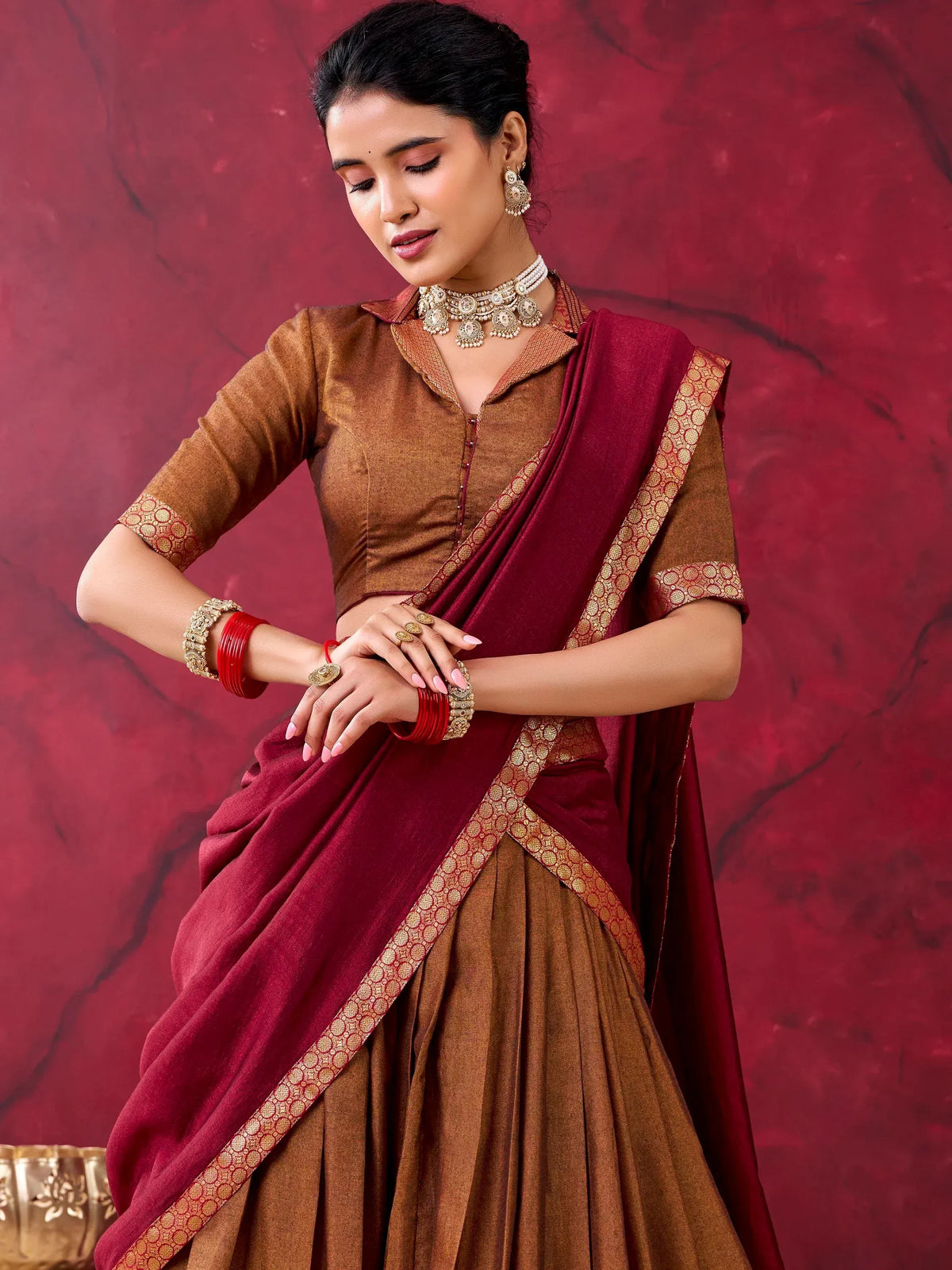 Woman wearing a brown and maroon designer lehenga choli with traditional jewelry