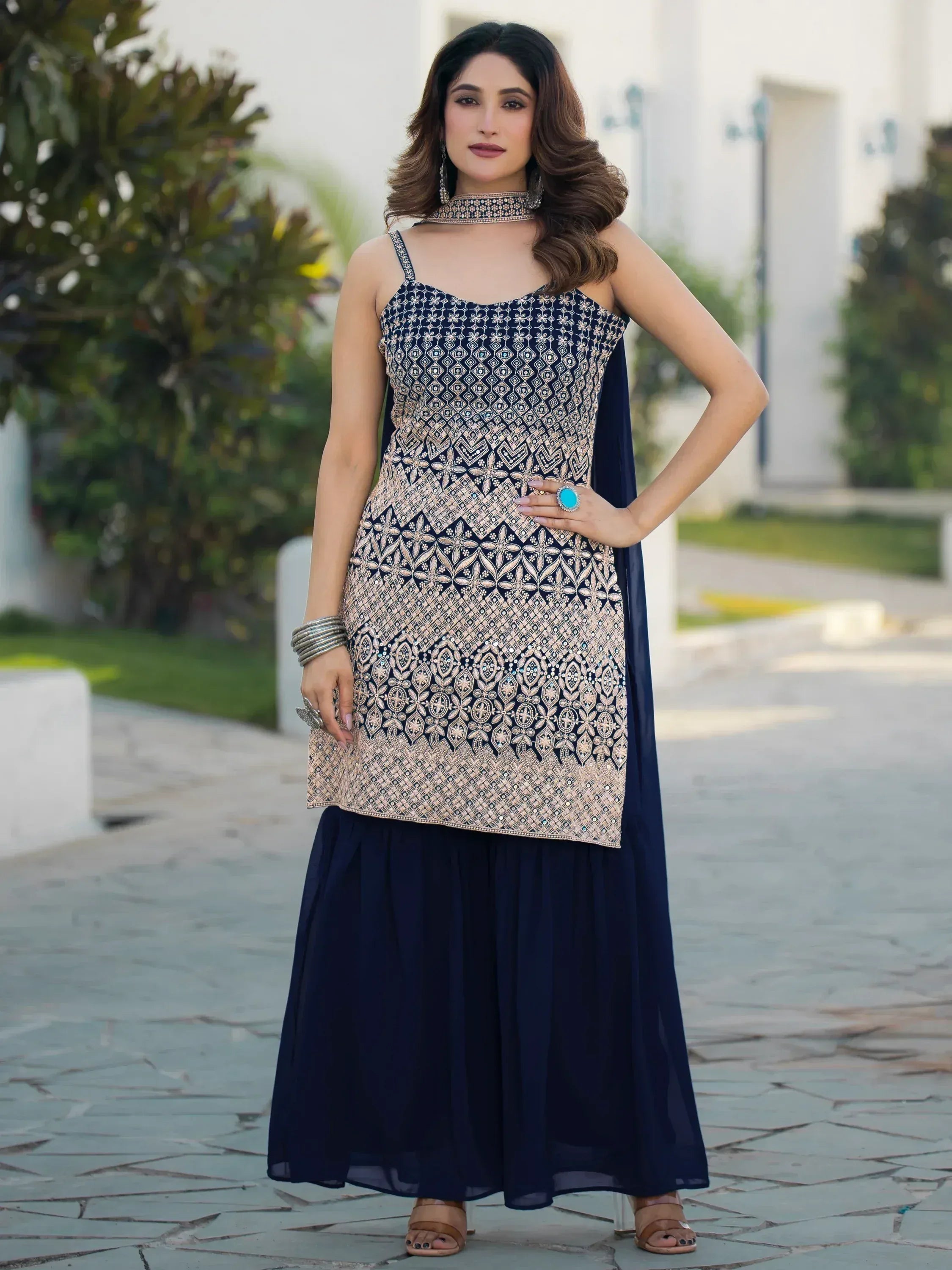 Navy blue embroidered ethnic gown with gold patterns, paired with matching skirt and statement jewelry for festive occasions.