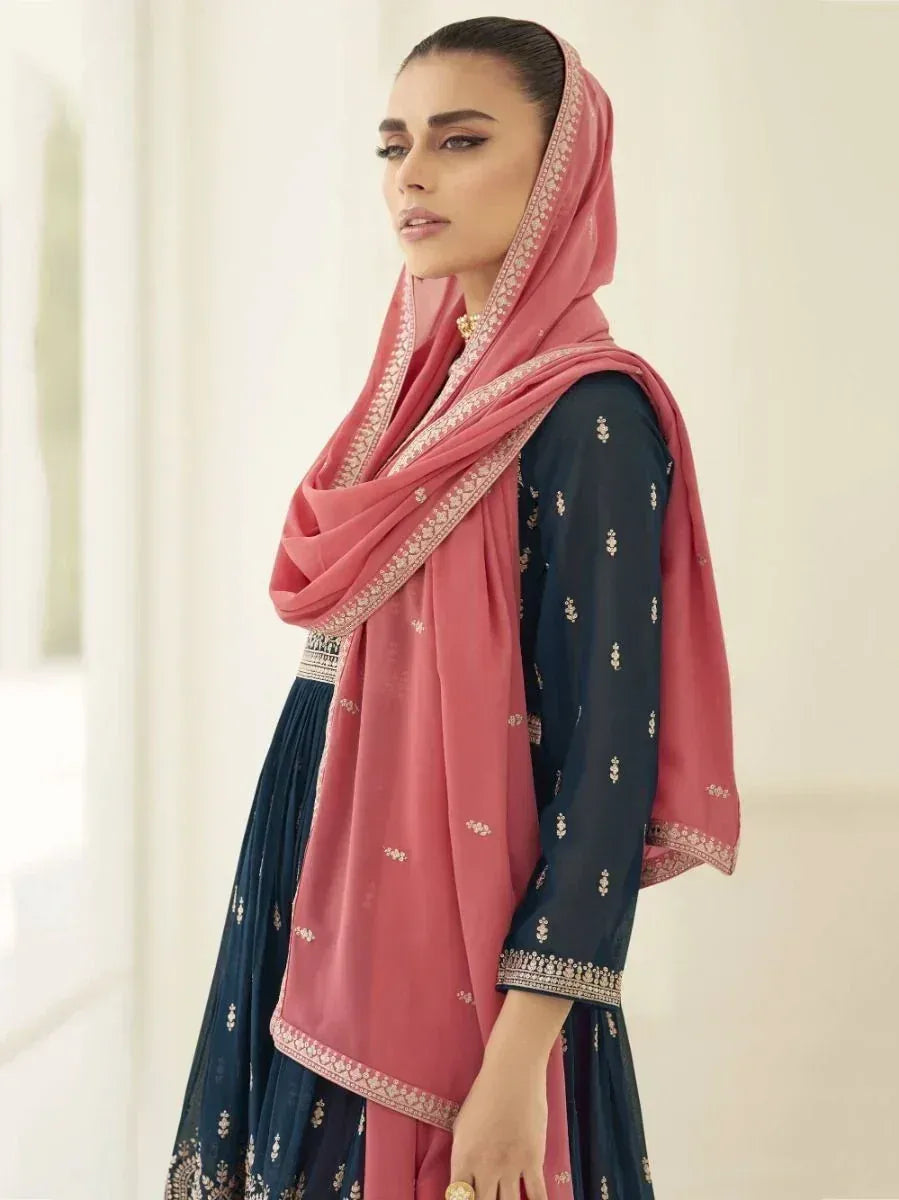 Woman in navy blue embroidered ethnic gown with a pink dupatta, side profile pose