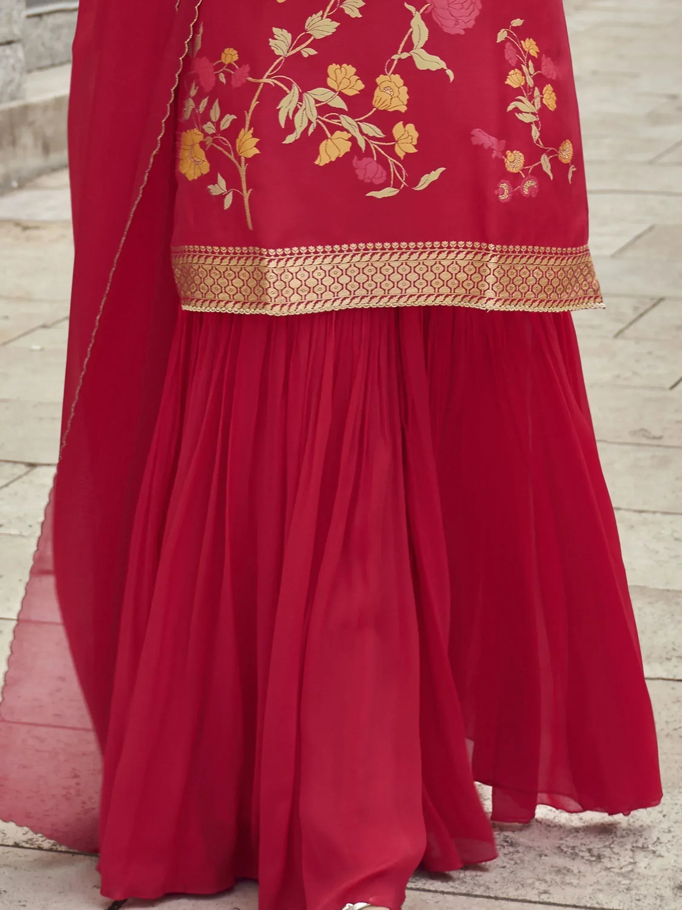 Red ethnic gown with floral embroidery and golden border, perfect for Indian celebrations.