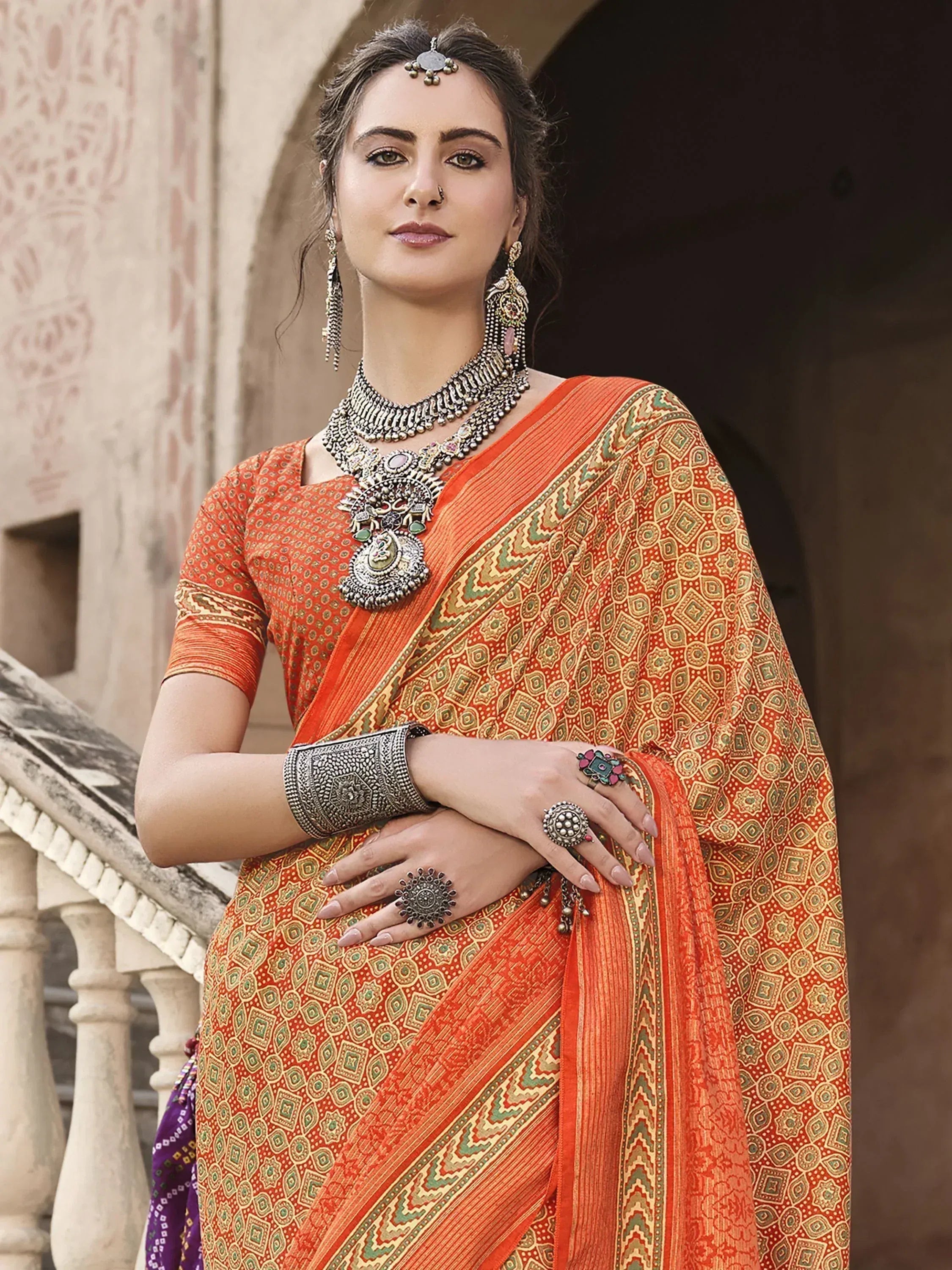 Woman in orange printed saree with ethnic jewelry, traditional Indian attire for festive occasions