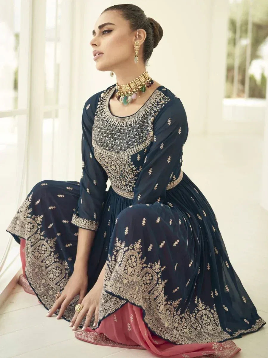 Woman in navy blue and gold embroidered ethnic gown with traditional jewelry, elegant pose