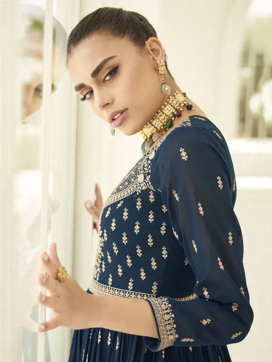 Woman in blue embroidered ethnic gown with gold jewelry, traditional Indian fashion