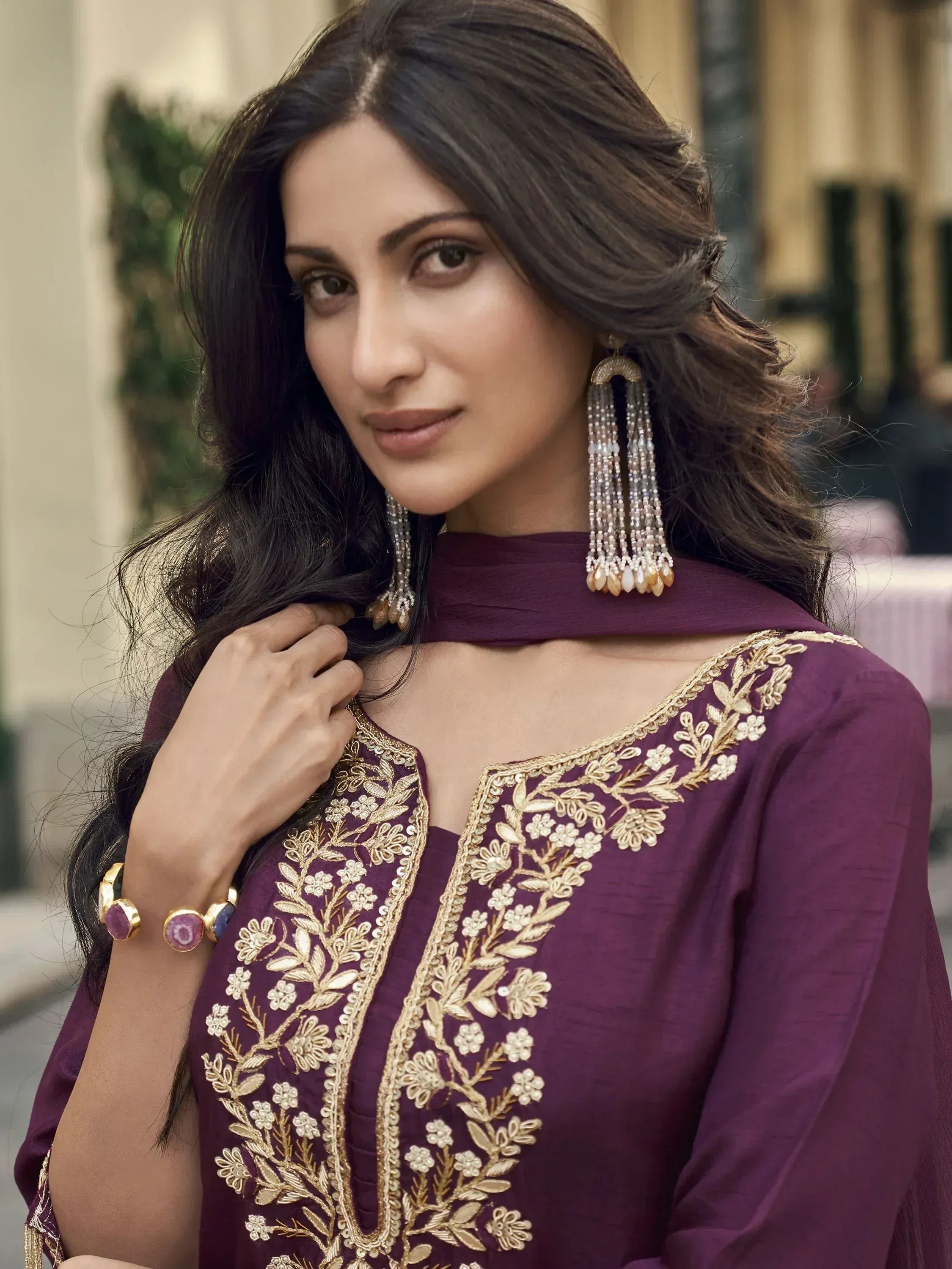 Woman in purple ethnic wear with gold floral embroidery, matching dupatta and statement earrings