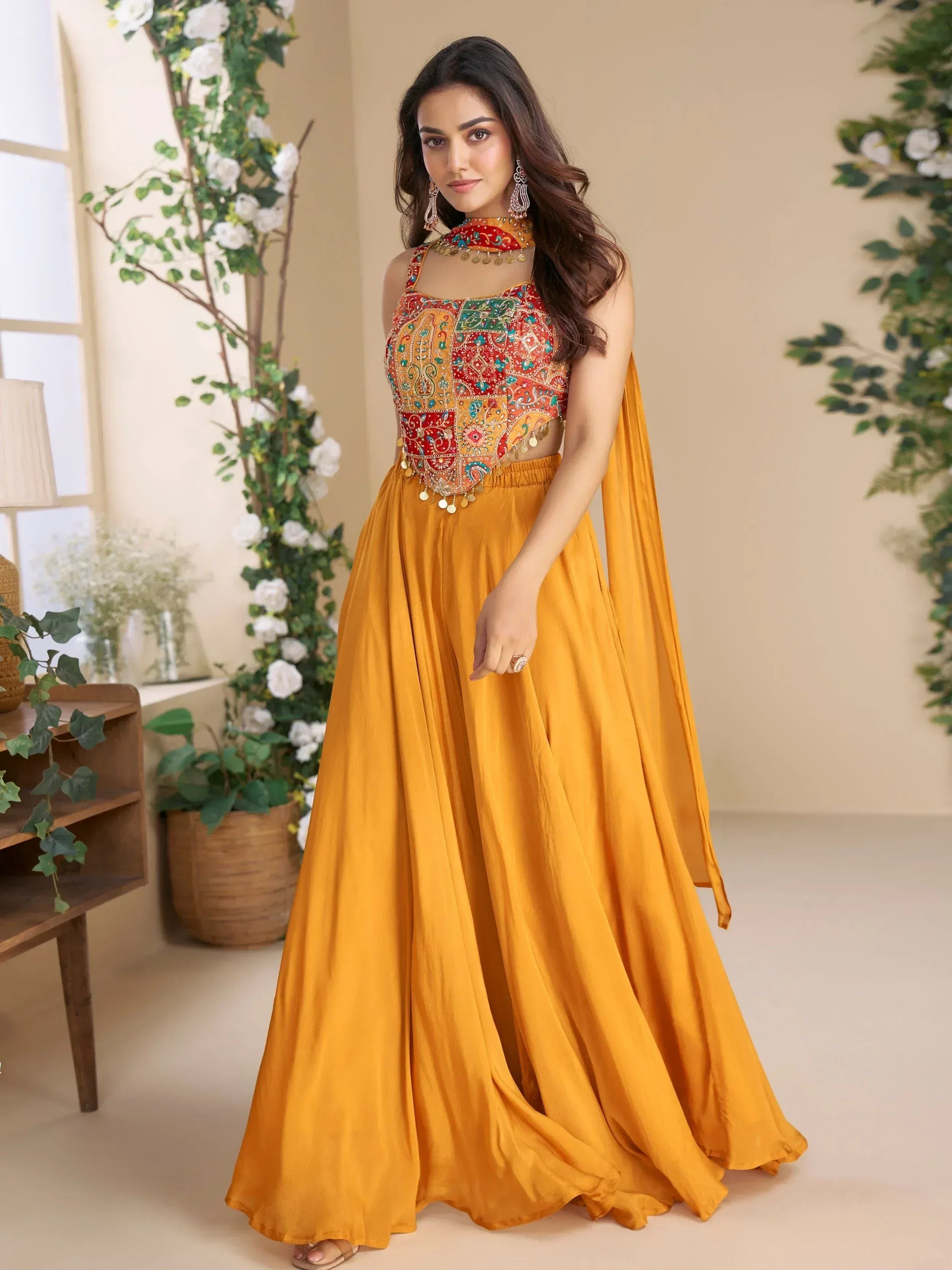 Woman in vibrant yellow ethnic gown with colorful embroidered top and coin detailing, perfect for Indian festive occasions.