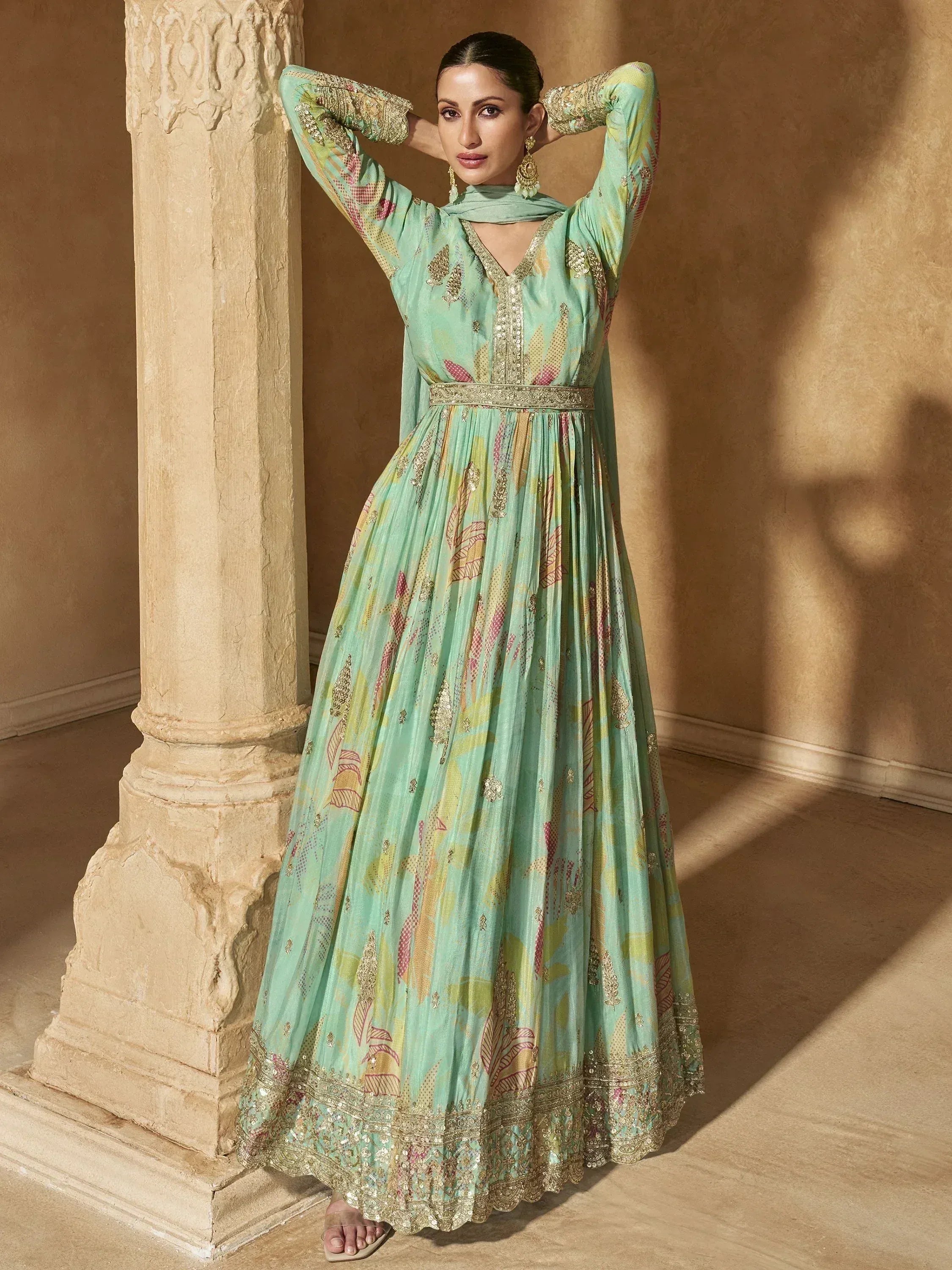 Elegant mint green ethnic gown with floral embroidery and gold detailing, styled with traditional jewelry.