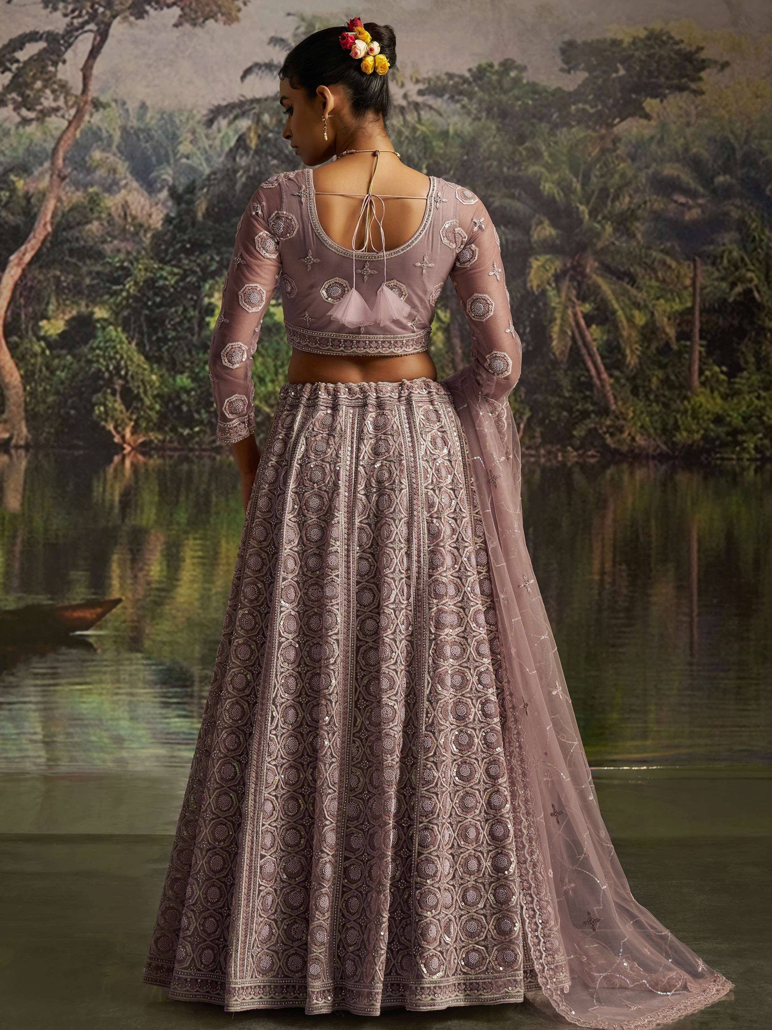 Elegant mauve lehenga choli with intricate embroidery, sheer sleeves, and floral hair accessory, perfect for Indian ethnic occasions.