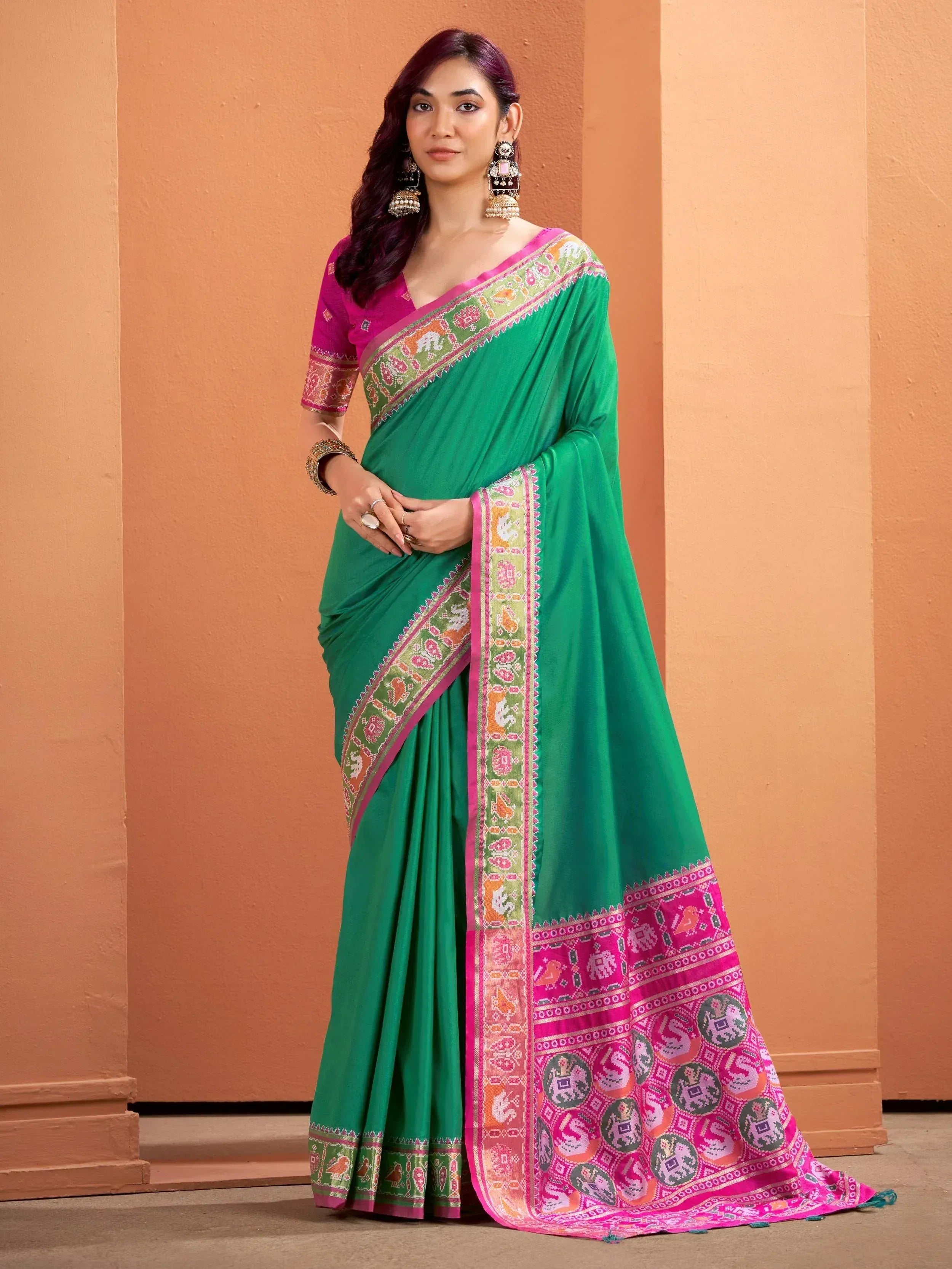 Green saree with pink border and traditional motifs, paired with matching blouse for ethnic wear