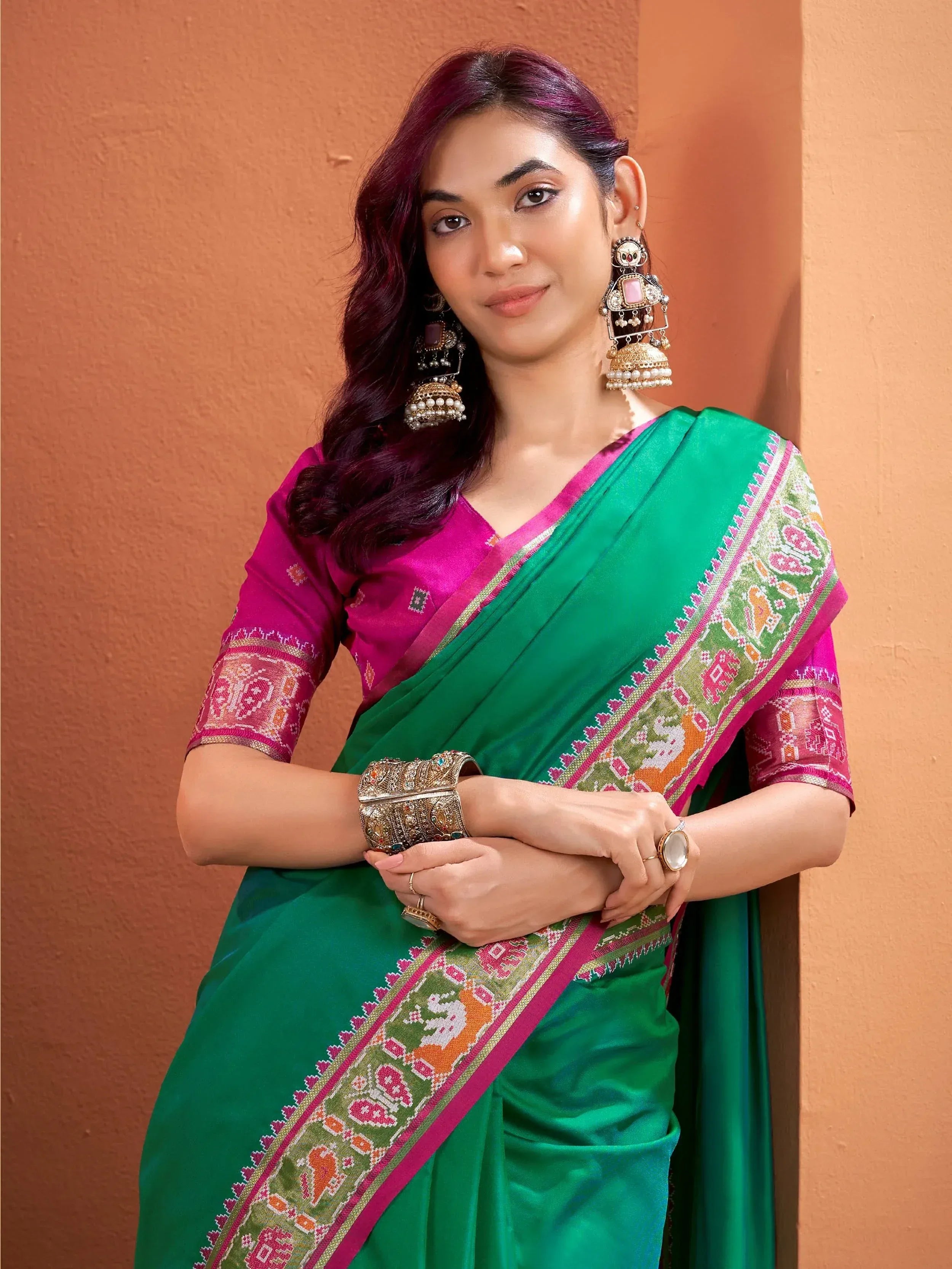Green and pink ethnic saree with intricate border, paired with designer blouse and traditional jewelry for festive occasions.