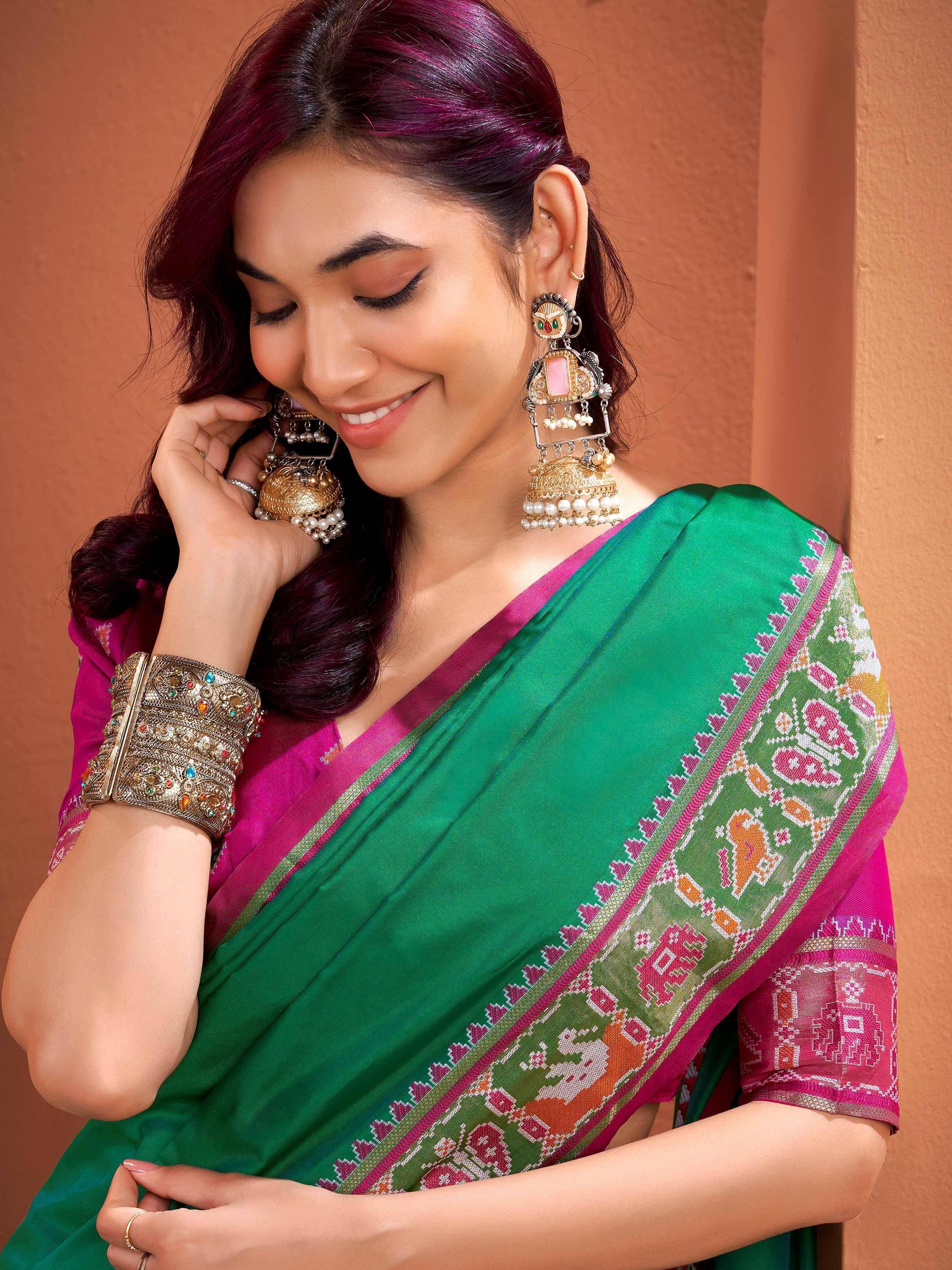 Woman in green and pink ethnic saree with traditional jewelry, perfect for festive occasions.