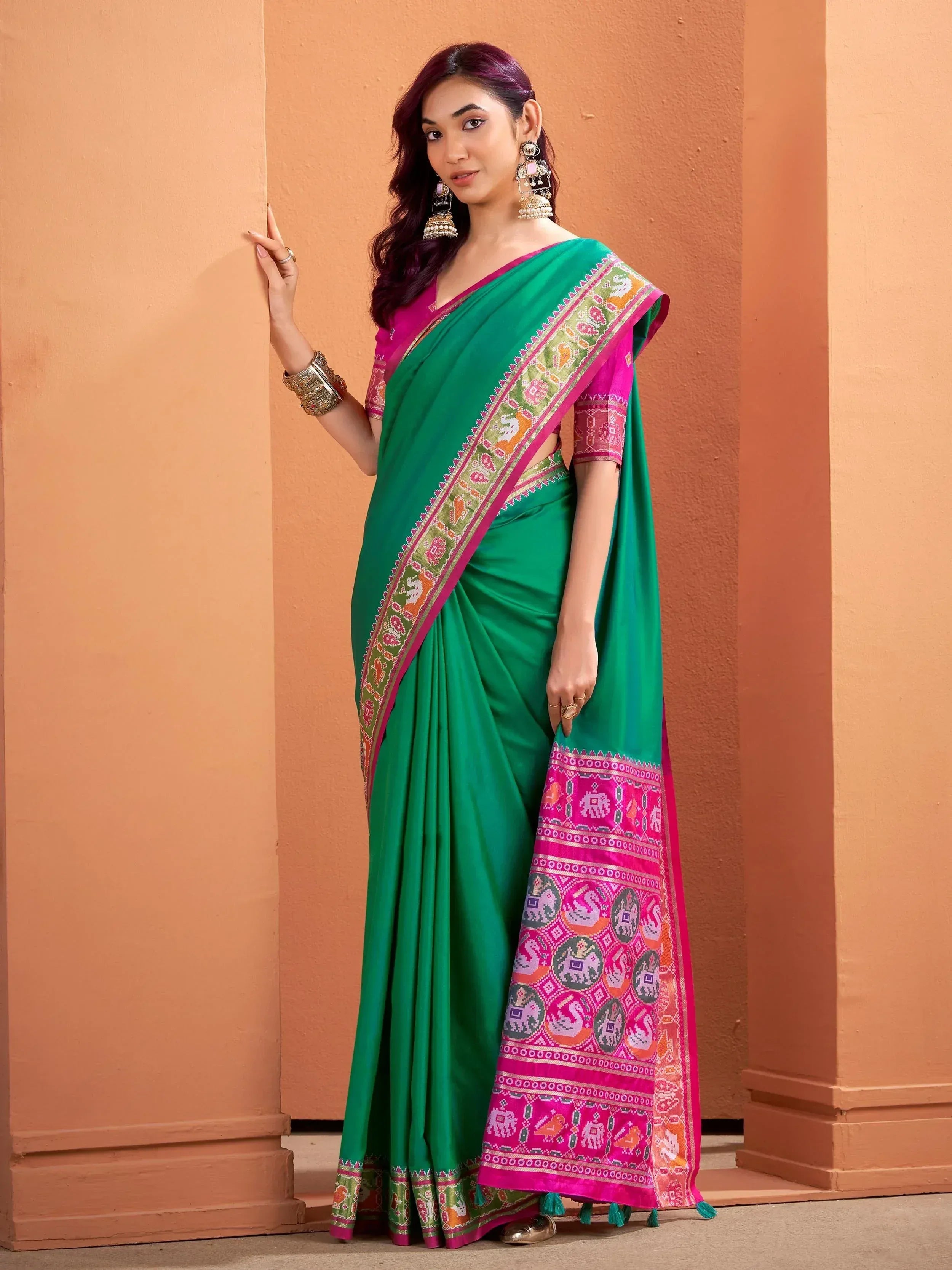 Green and pink ethnic saree with elephant print border, styled with traditional jewelry for festive occasions.