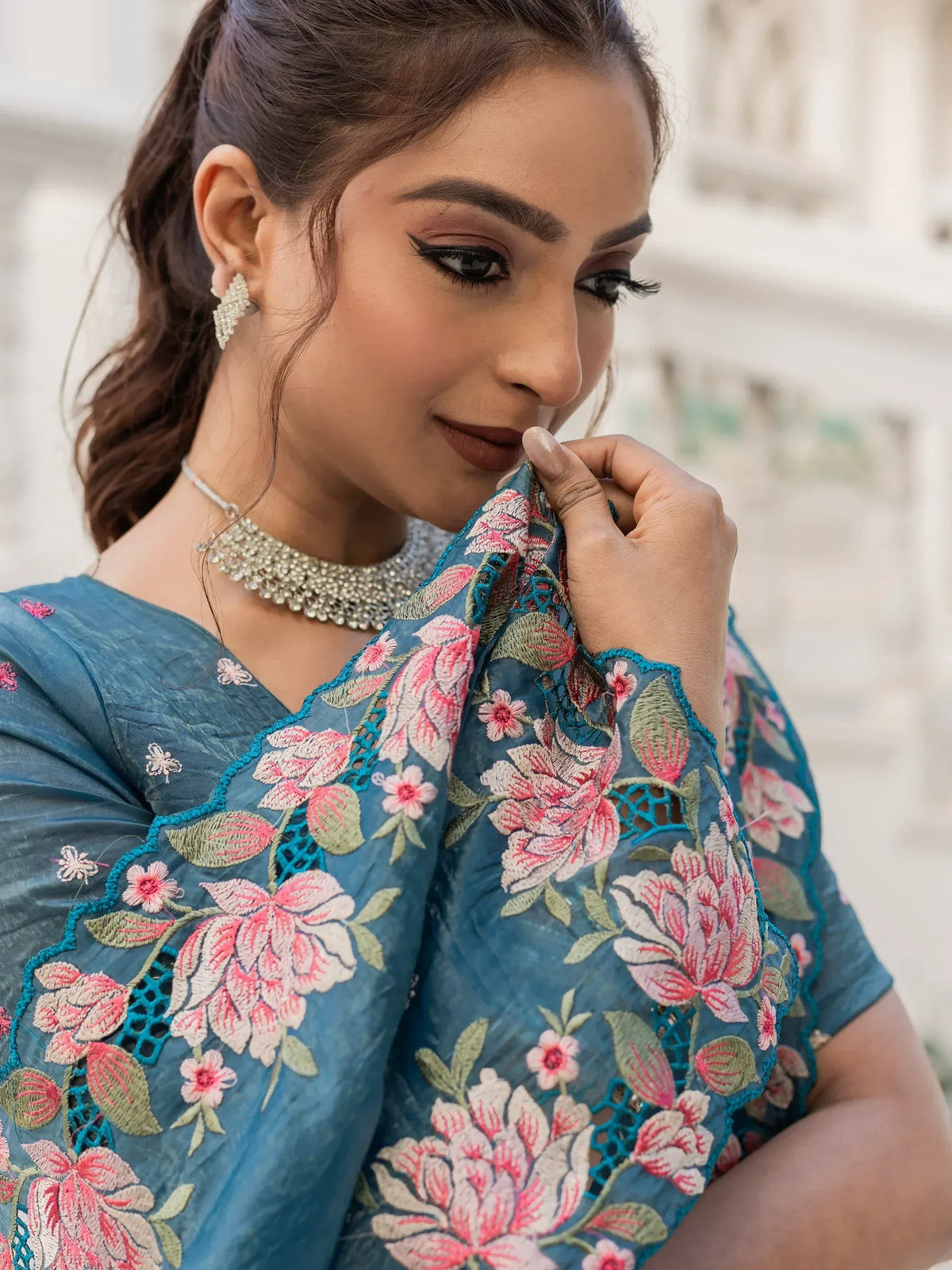 Blue floral embroidered ethnic gown with pink and green detailing, styled with statement jewelry