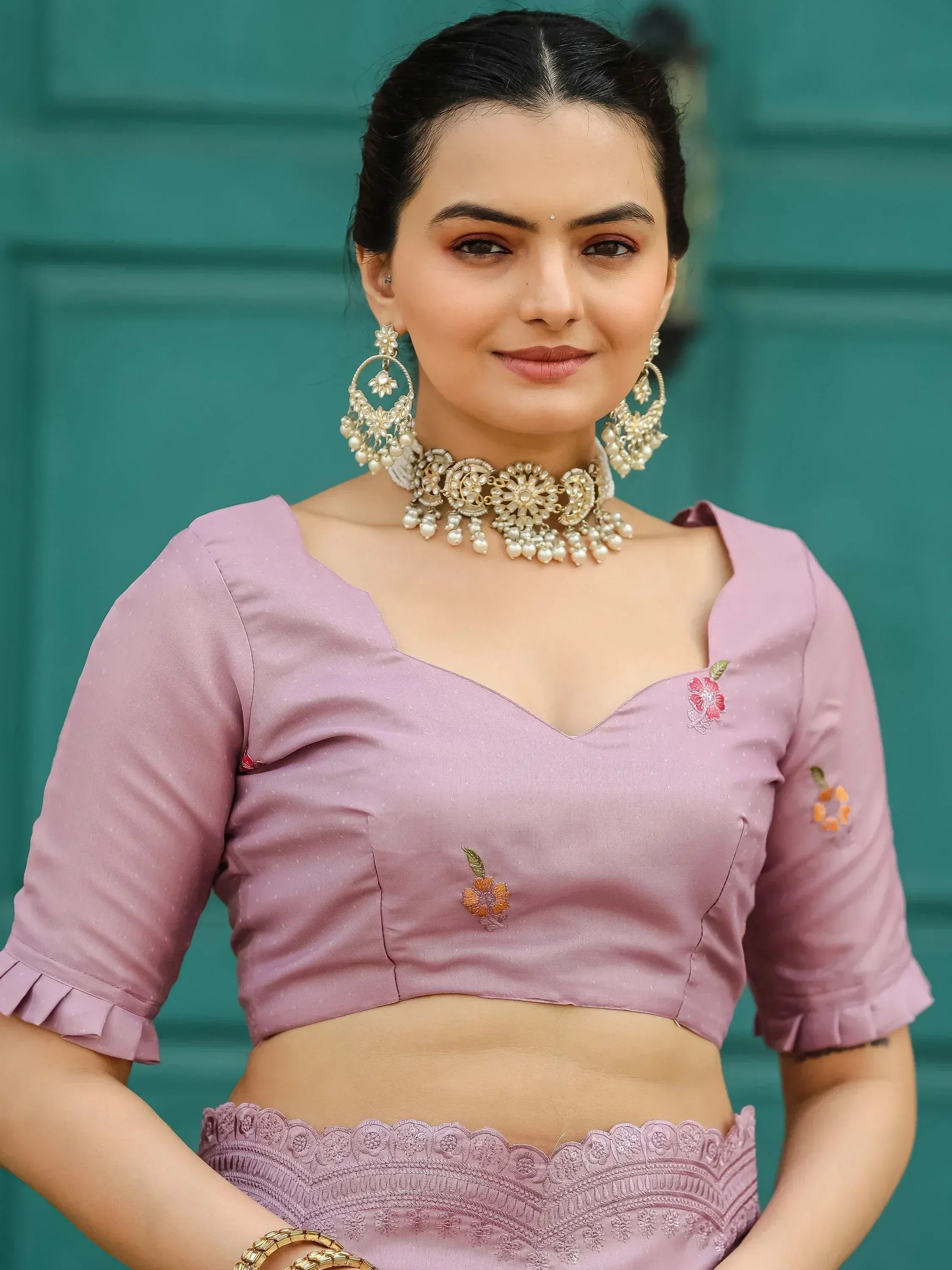 Pink embroidered lehenga choli with floral details and gold jewelry, perfect for Indian ethnic wear