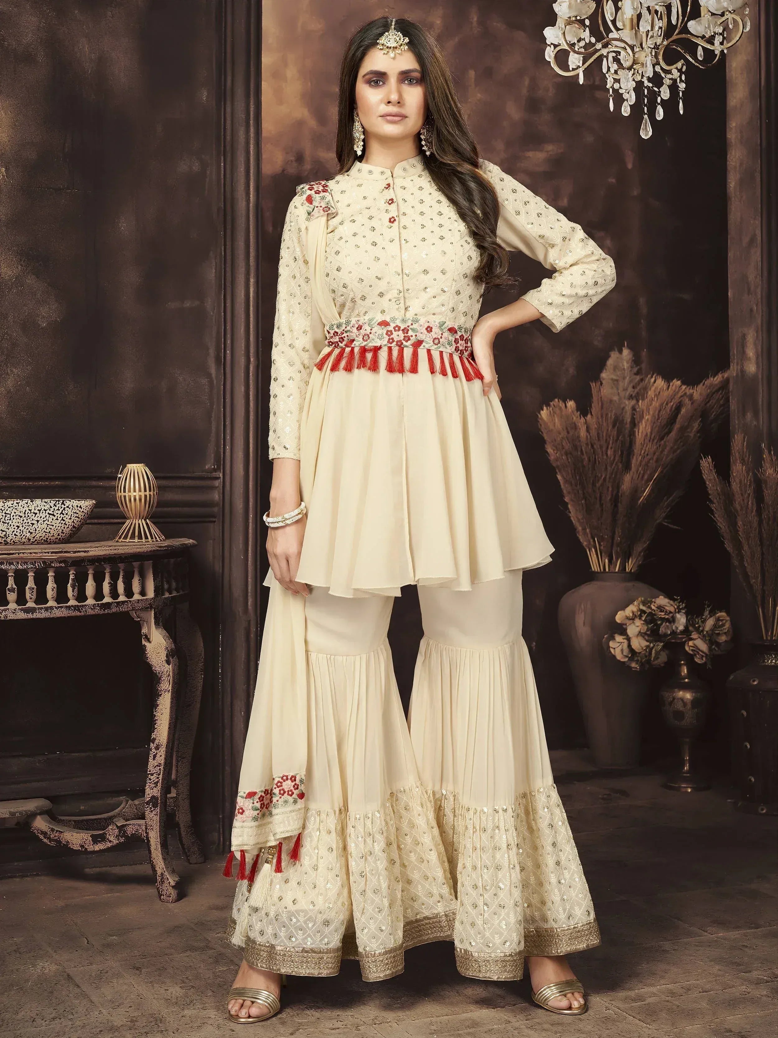 Woman wearing cream embroidered ethnic sharara suit with red tassel detailing