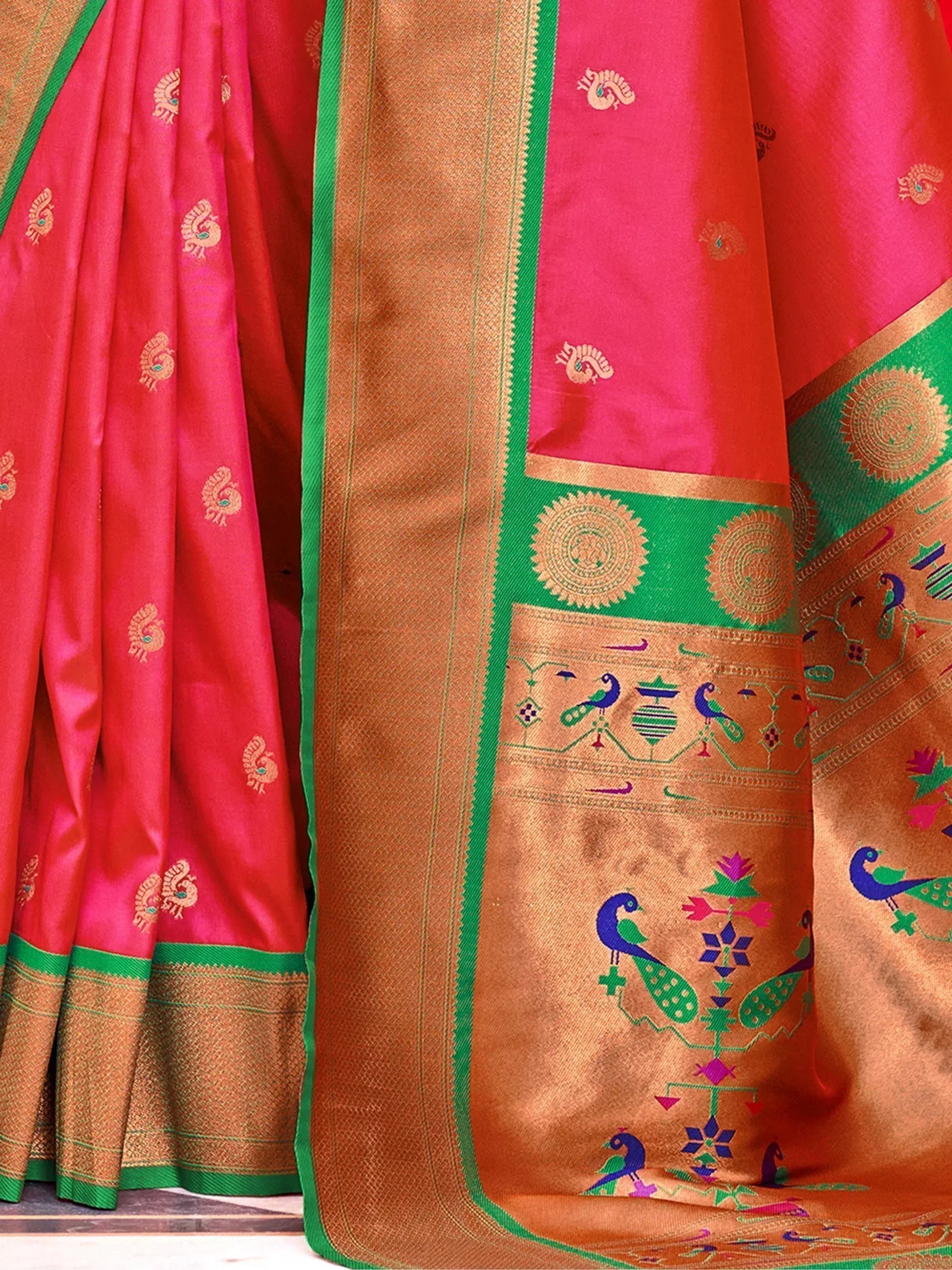 Vibrant pink and gold saree with peacock motifs, green border, and intricate temple designs for ethnic wear