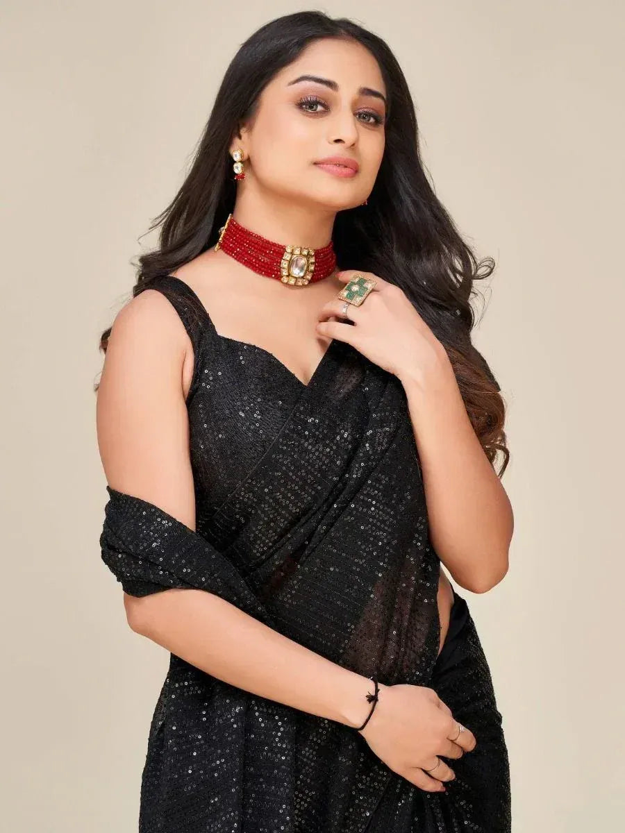 Woman in black sequin saree with red choker, elegant Indian ethnic wear for festive occasions