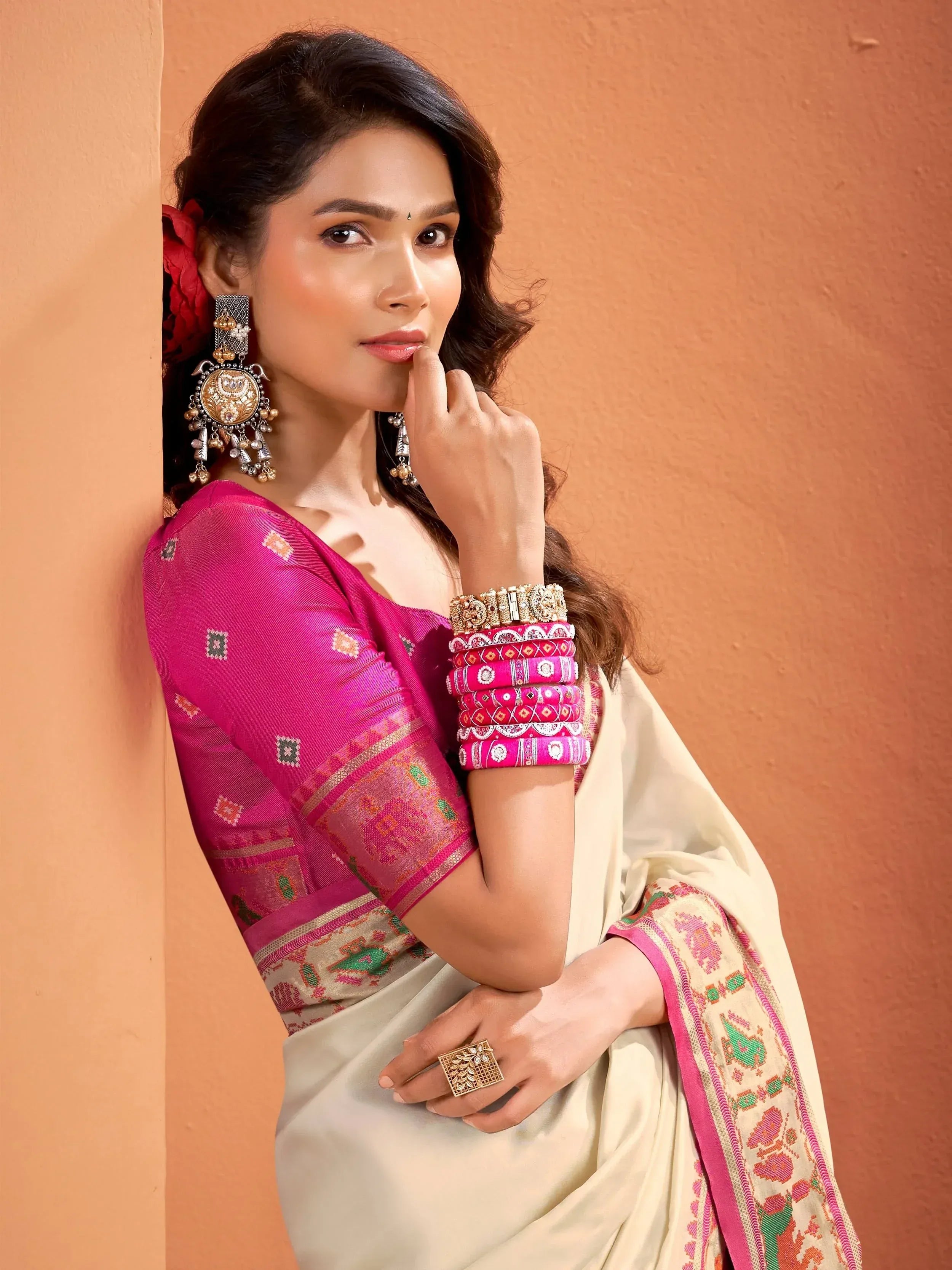 Woman in elegant pink and cream saree with embroidered blouse, traditional jewelry, and bangles