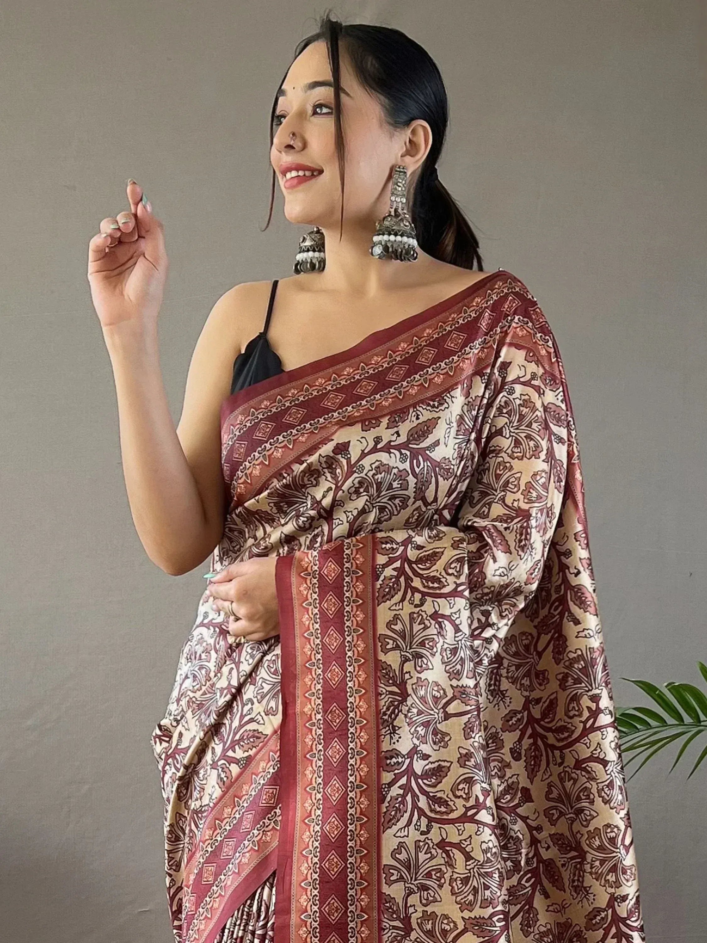 Woman in elegant maroon and cream floral saree with traditional jewelry, perfect for Indian ethnic wear occasions.