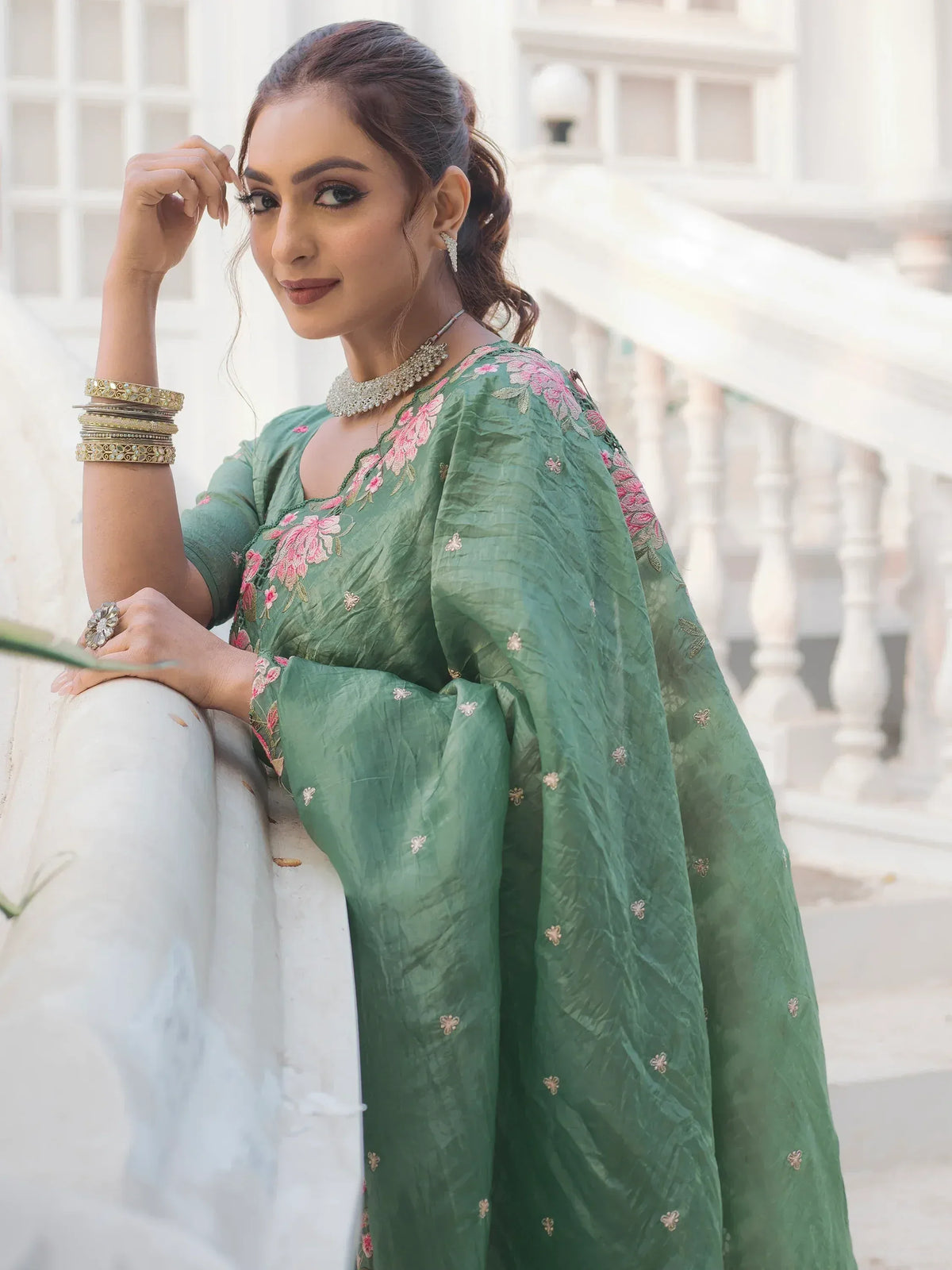 Green floral embroidered salwar kameez with pink detailing, styled with traditional jewelry for ethnic wear.