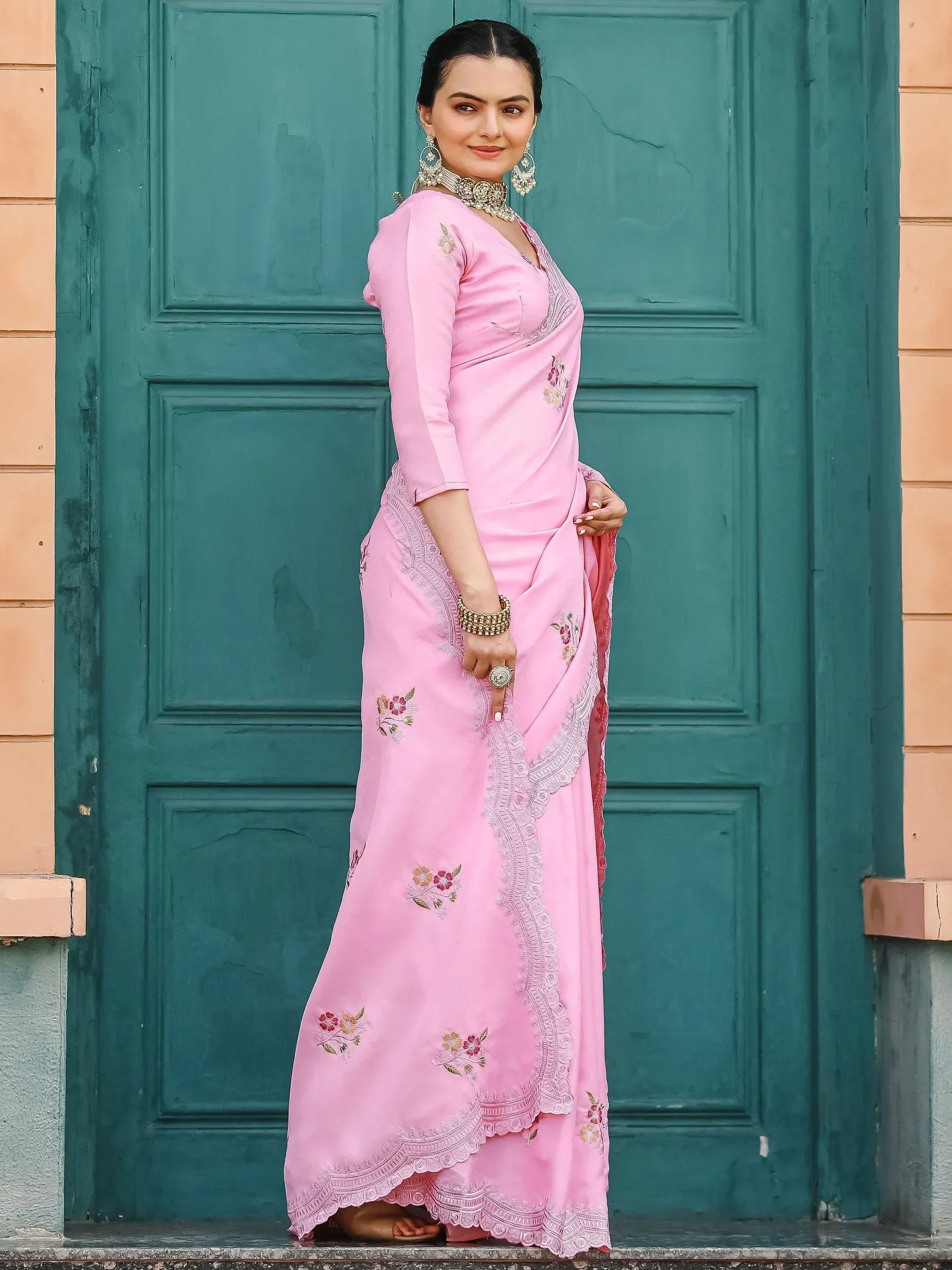 Pink embroidered saree with floral motifs and lace border, styled with traditional jewelry for ethnic wear.