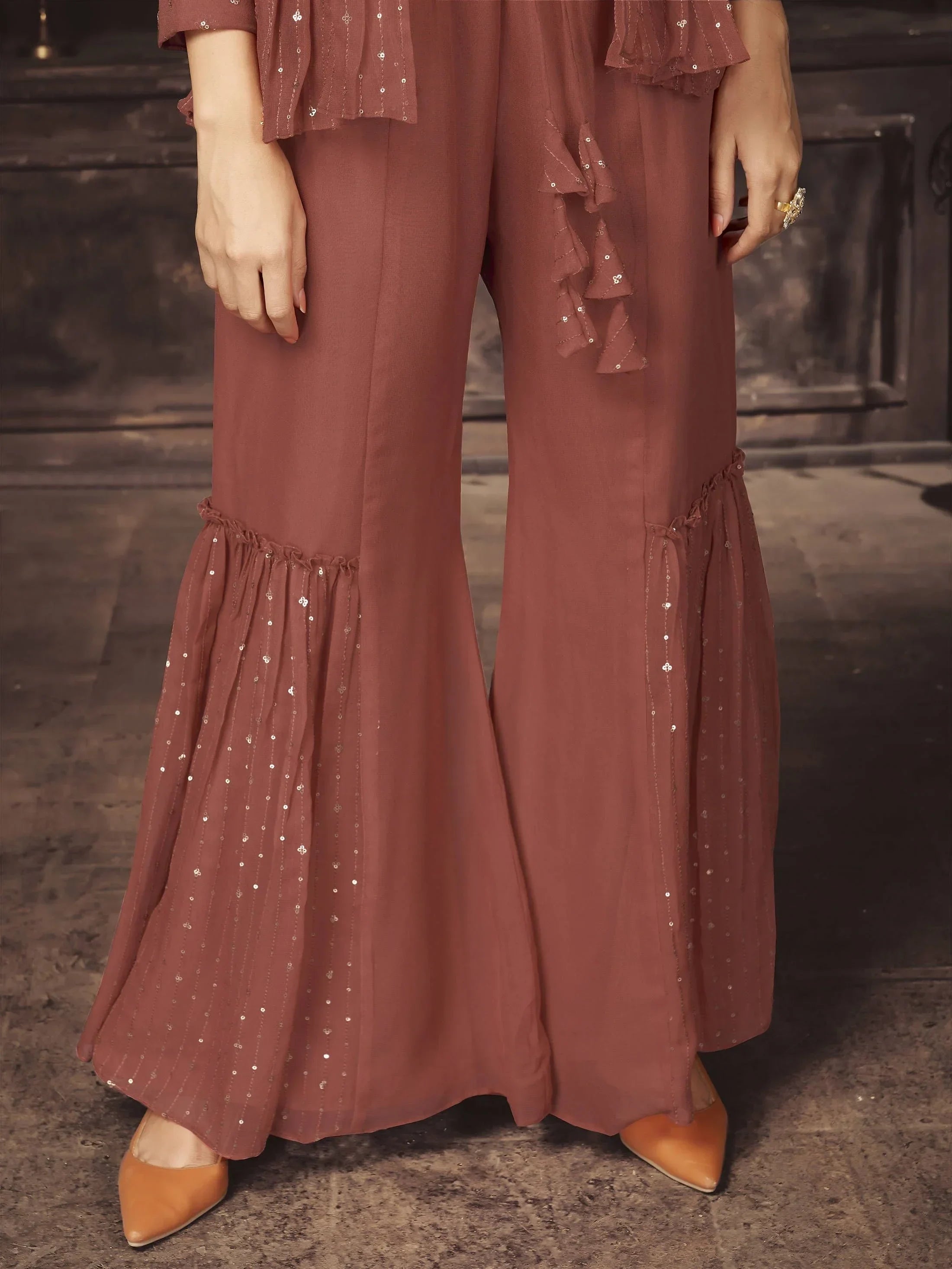 Close-up of woman wearing brown ethnic palazzo pants with sequin detailing and flared hem