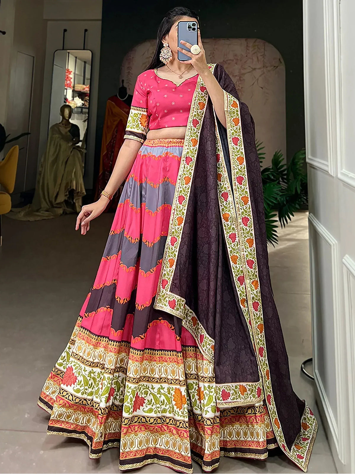 Woman wearing vibrant pink and purple printed lehenga choli with floral dupatta, perfect for Indian ethnic occasions