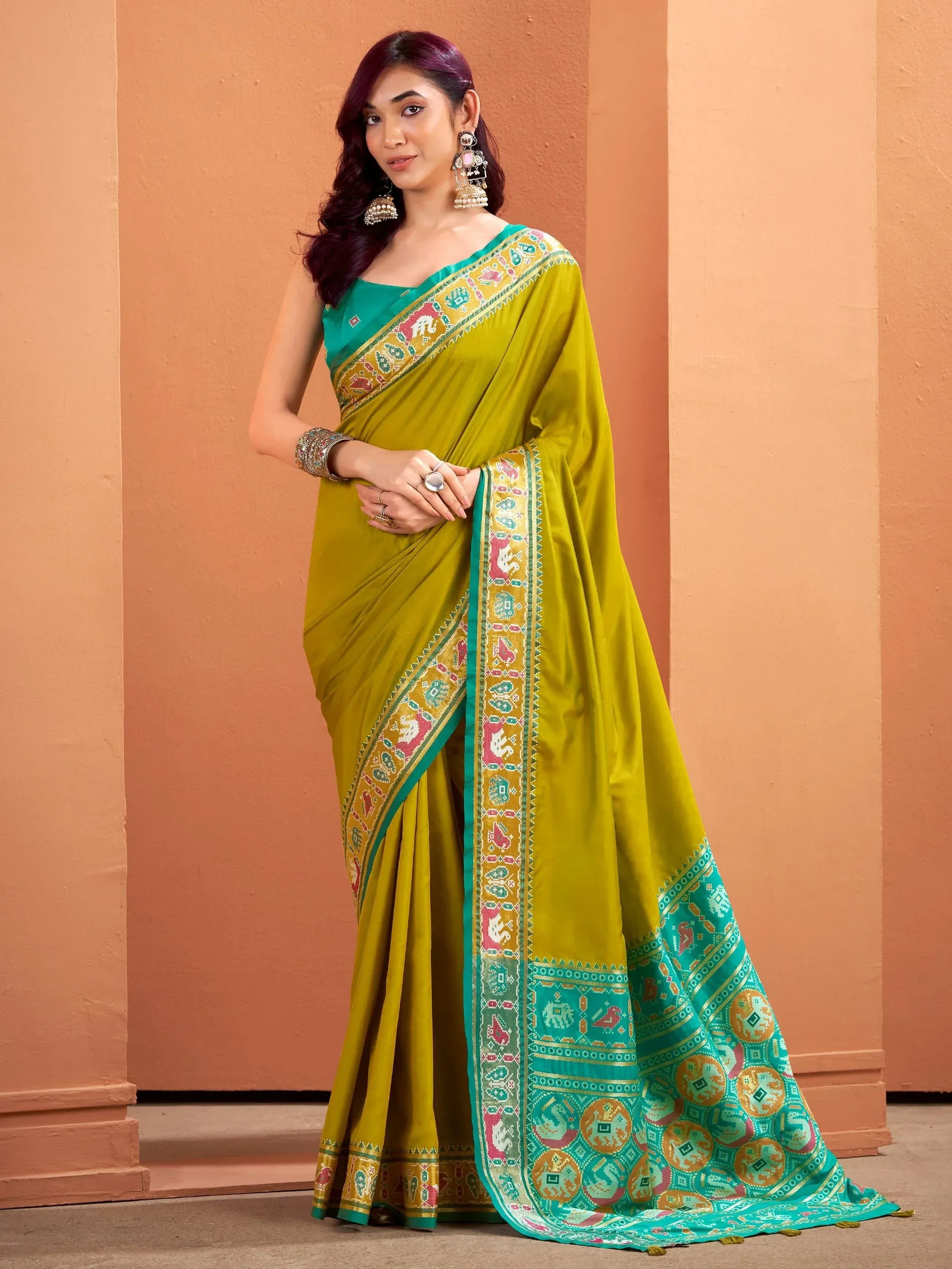 Woman in vibrant green and yellow ethnic saree with elephant print border, styled with traditional jewelry