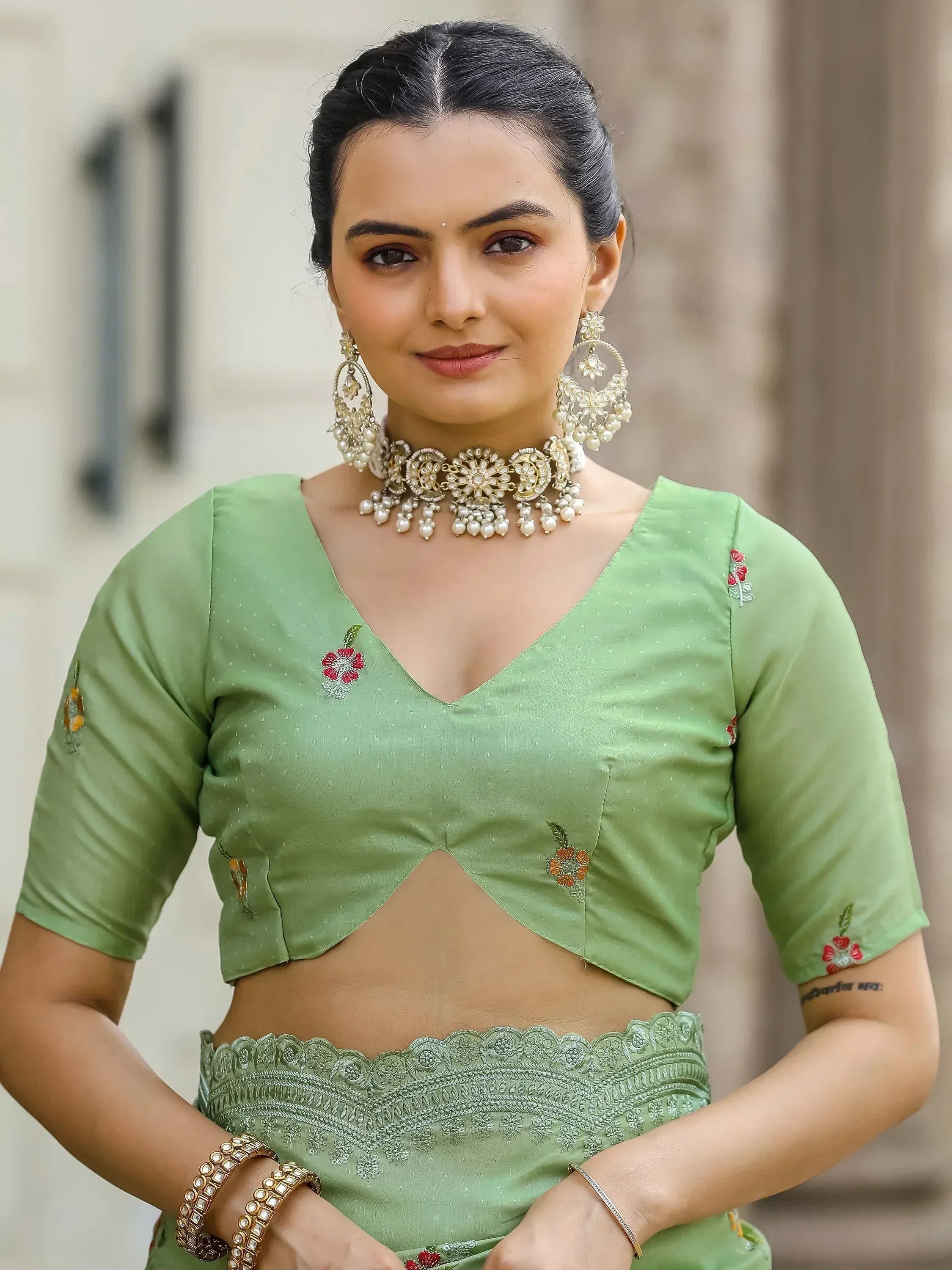 Green embroidered lehenga choli with floral motifs and pearl jewelry, perfect for Indian ethnic wear occasions.