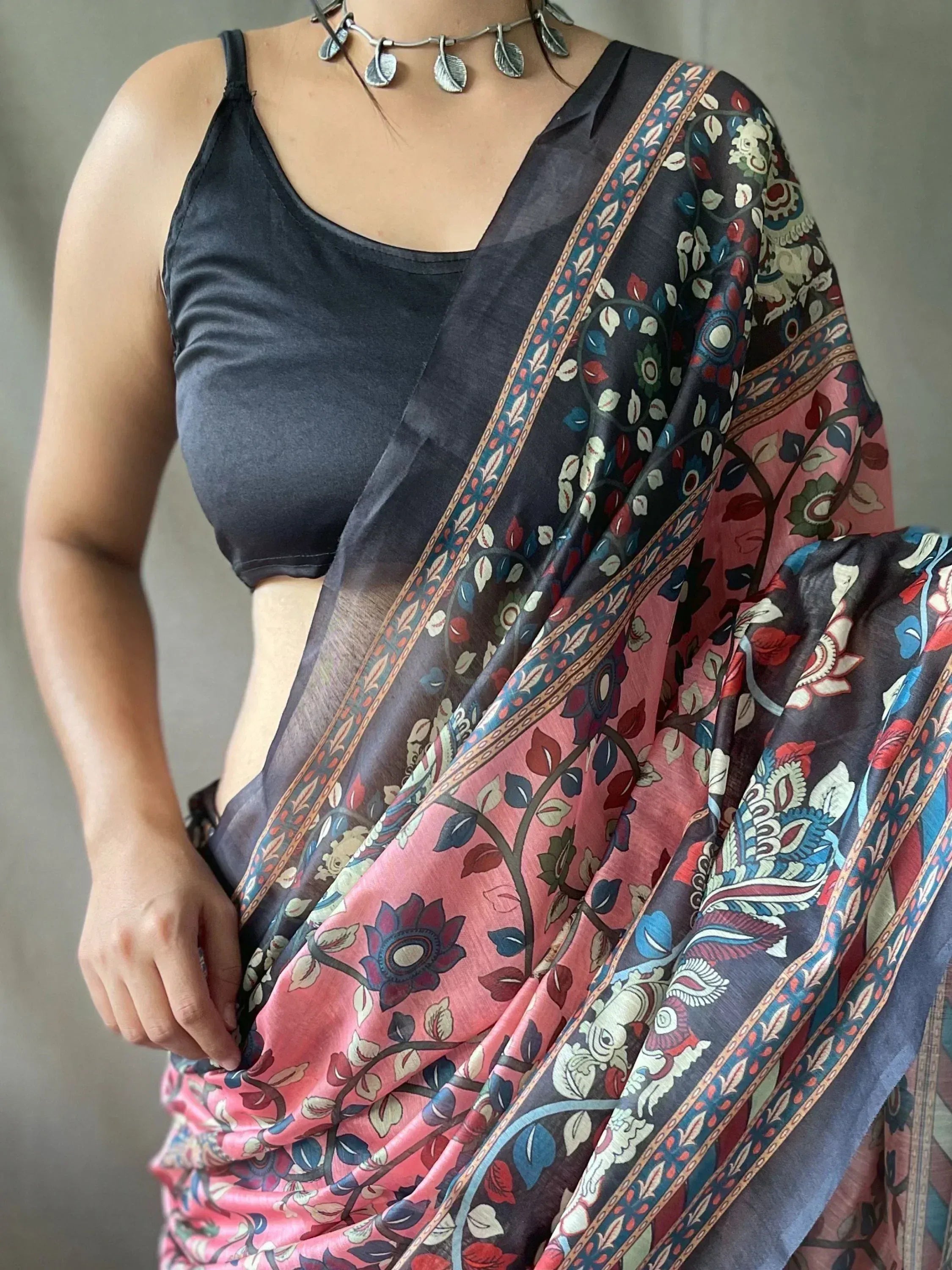 Floral printed saree with pink and navy blue hues, paired with black blouse and leaf necklace