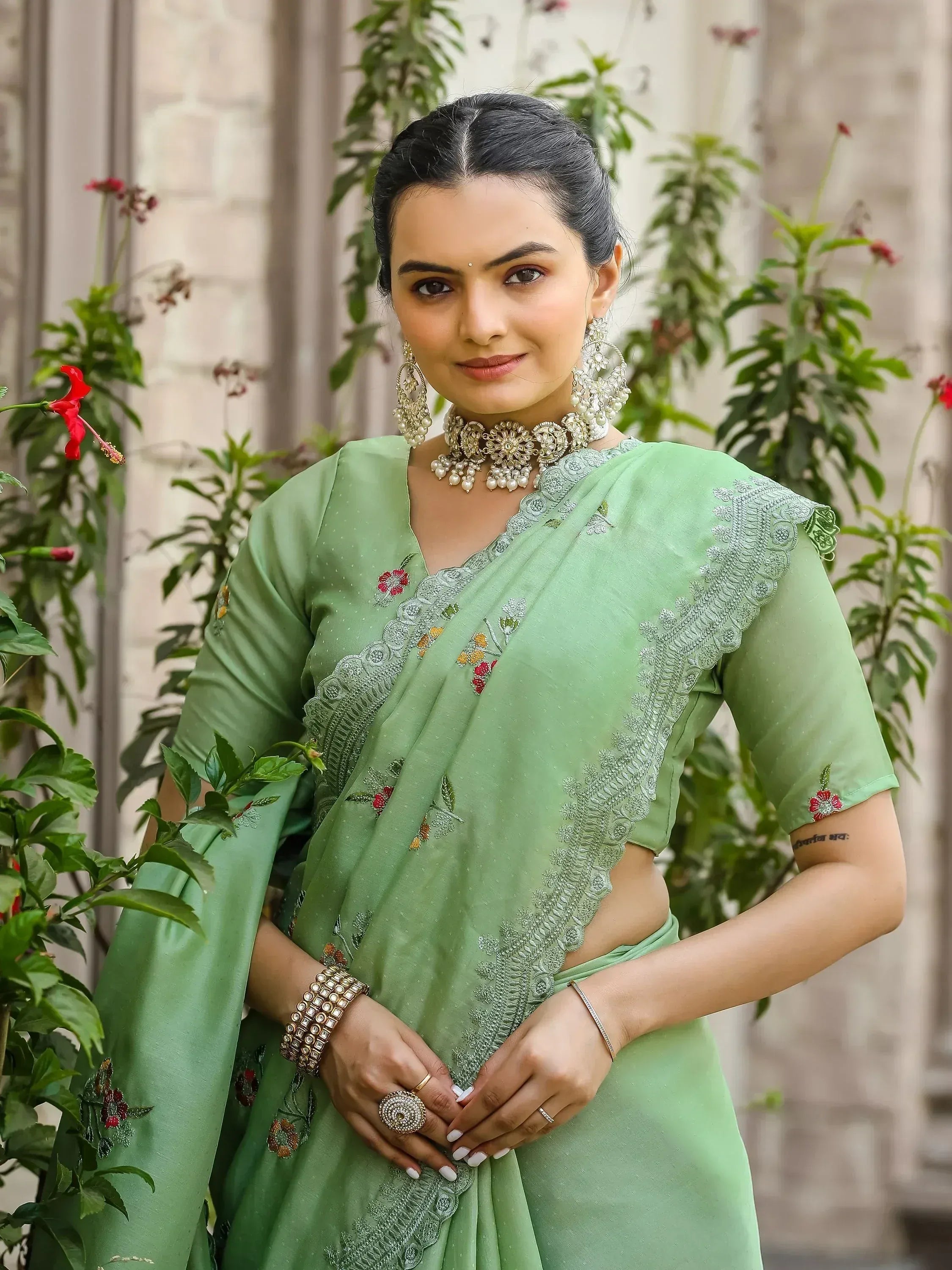 Woman in mint green embroidered saree with floral details and traditional jewelry, styled for ethnic occasions