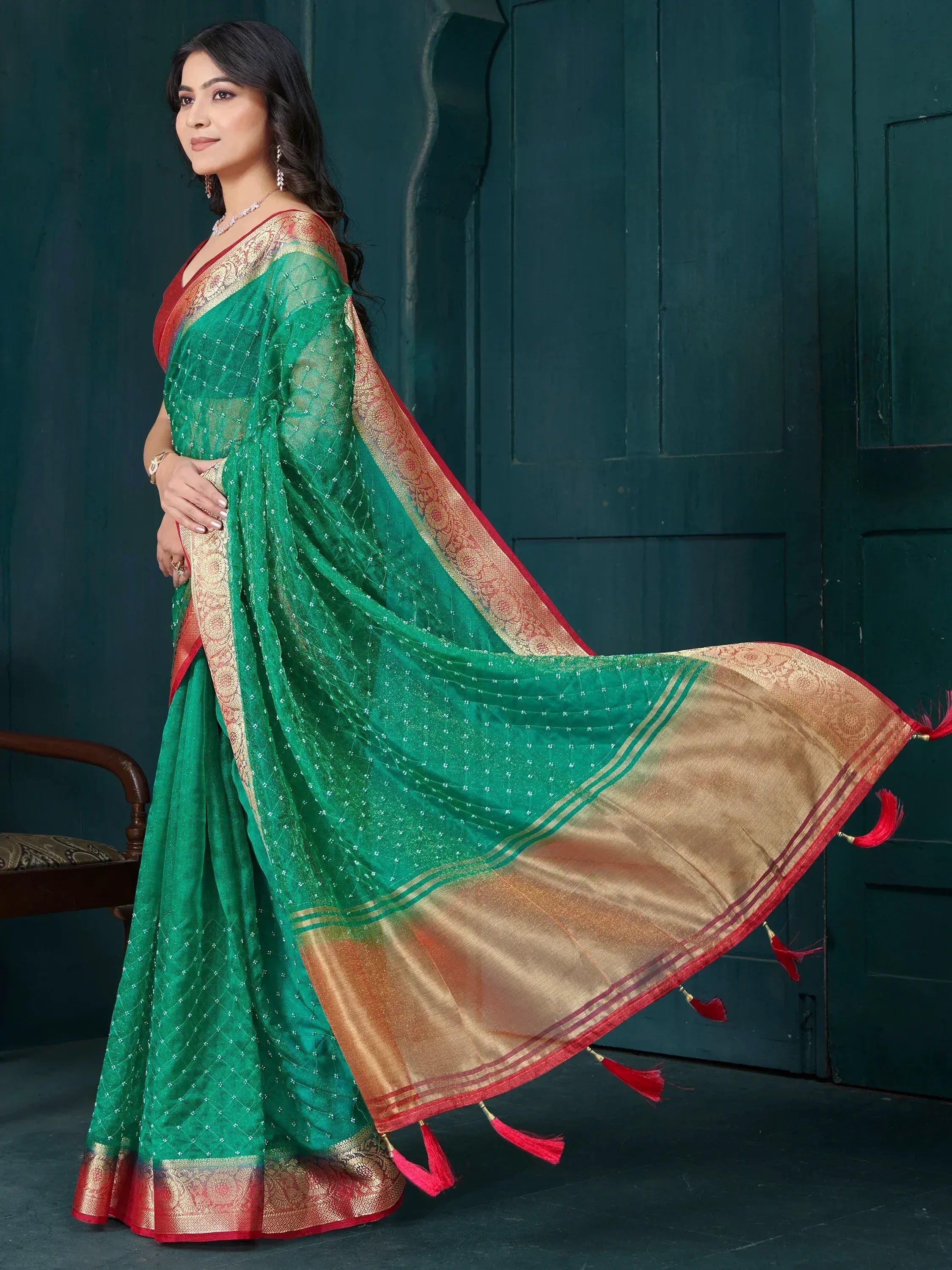 Green ethnic saree with gold border and red tassels, perfect for Indian festive occasions
