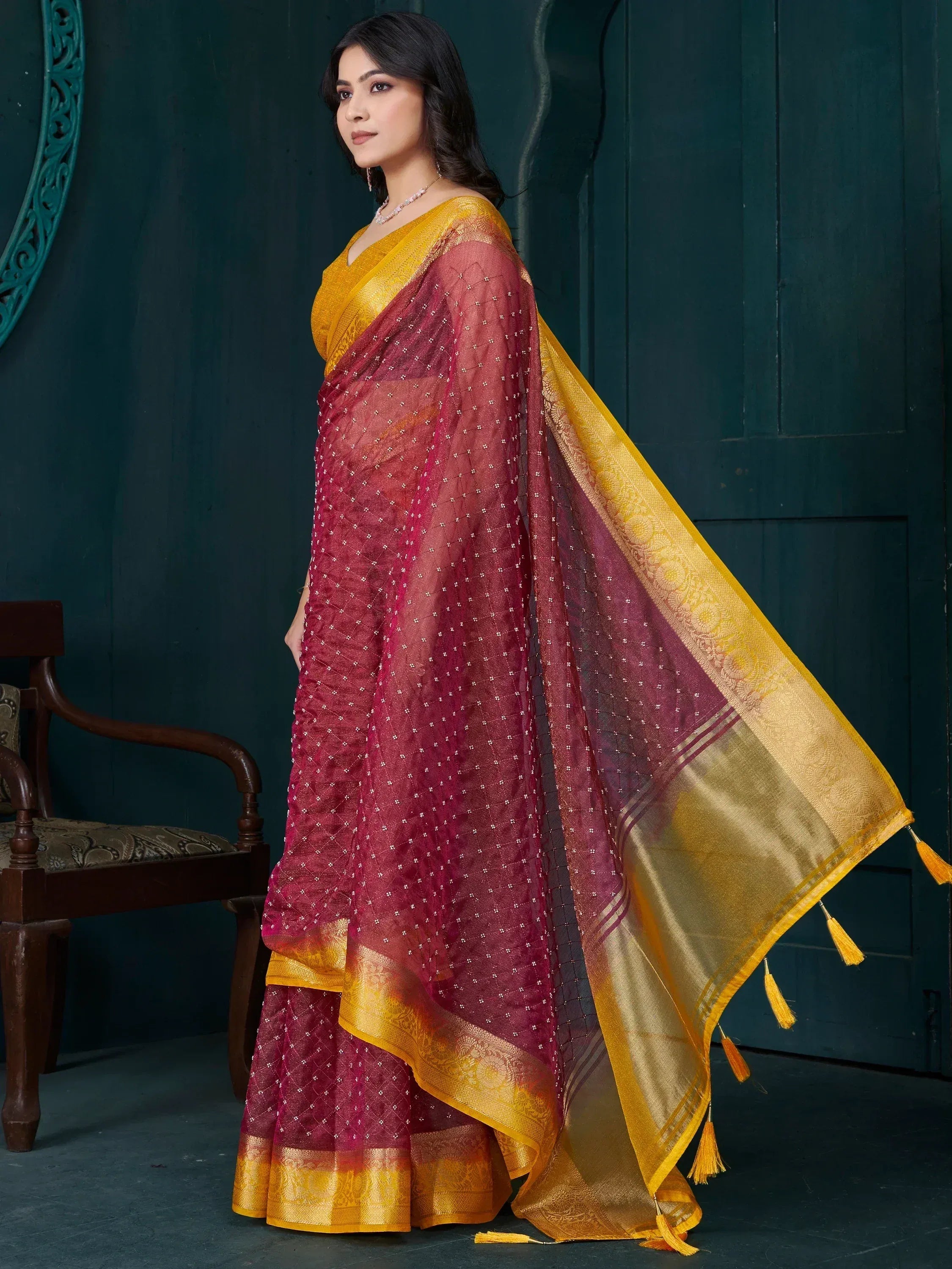 Maroon and gold designer saree with intricate embroidery and tassels, perfect for ethnic occasions.