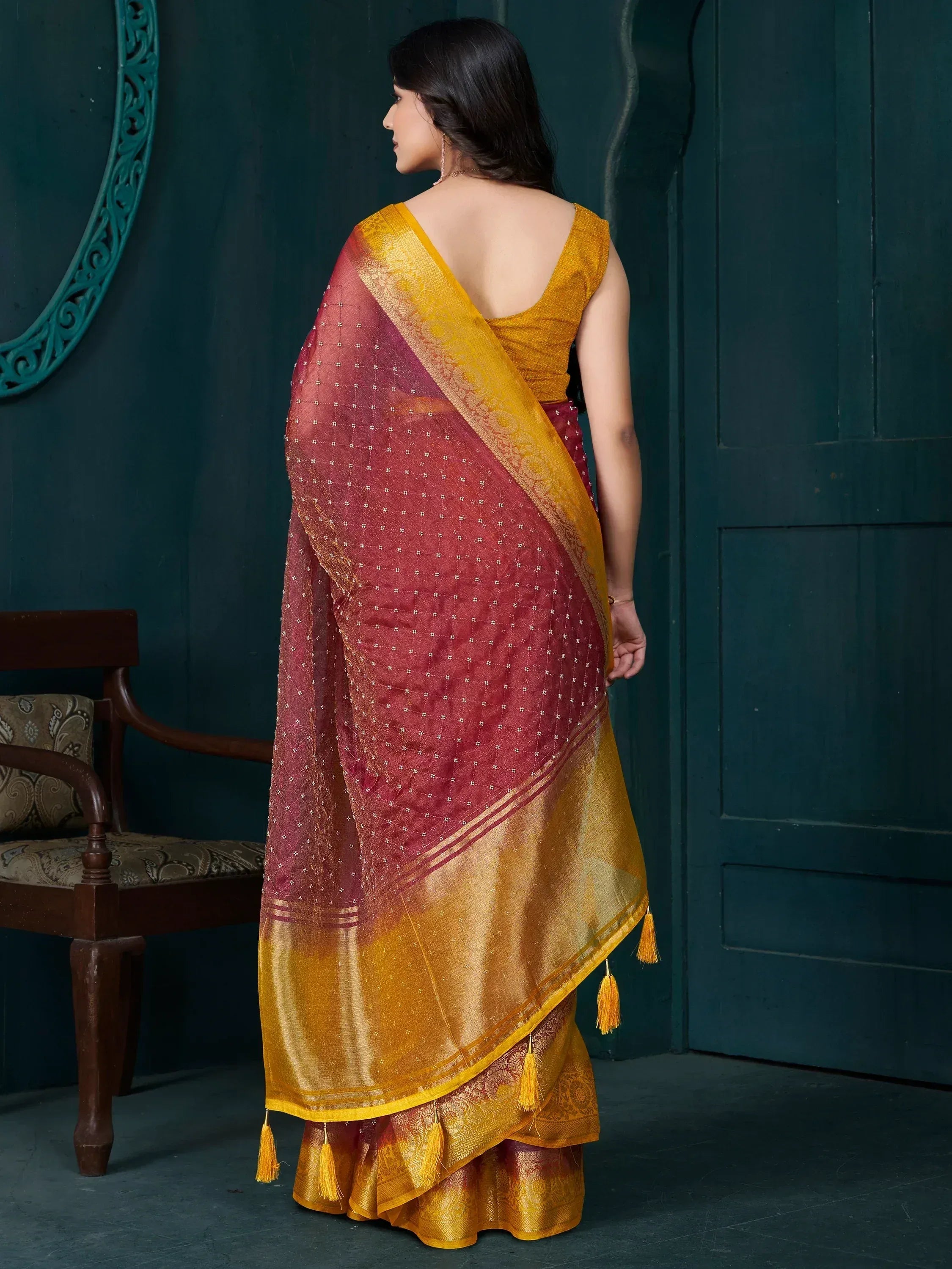 Maroon and gold saree with tassels and intricate embroidery, perfect for ethnic occasions.