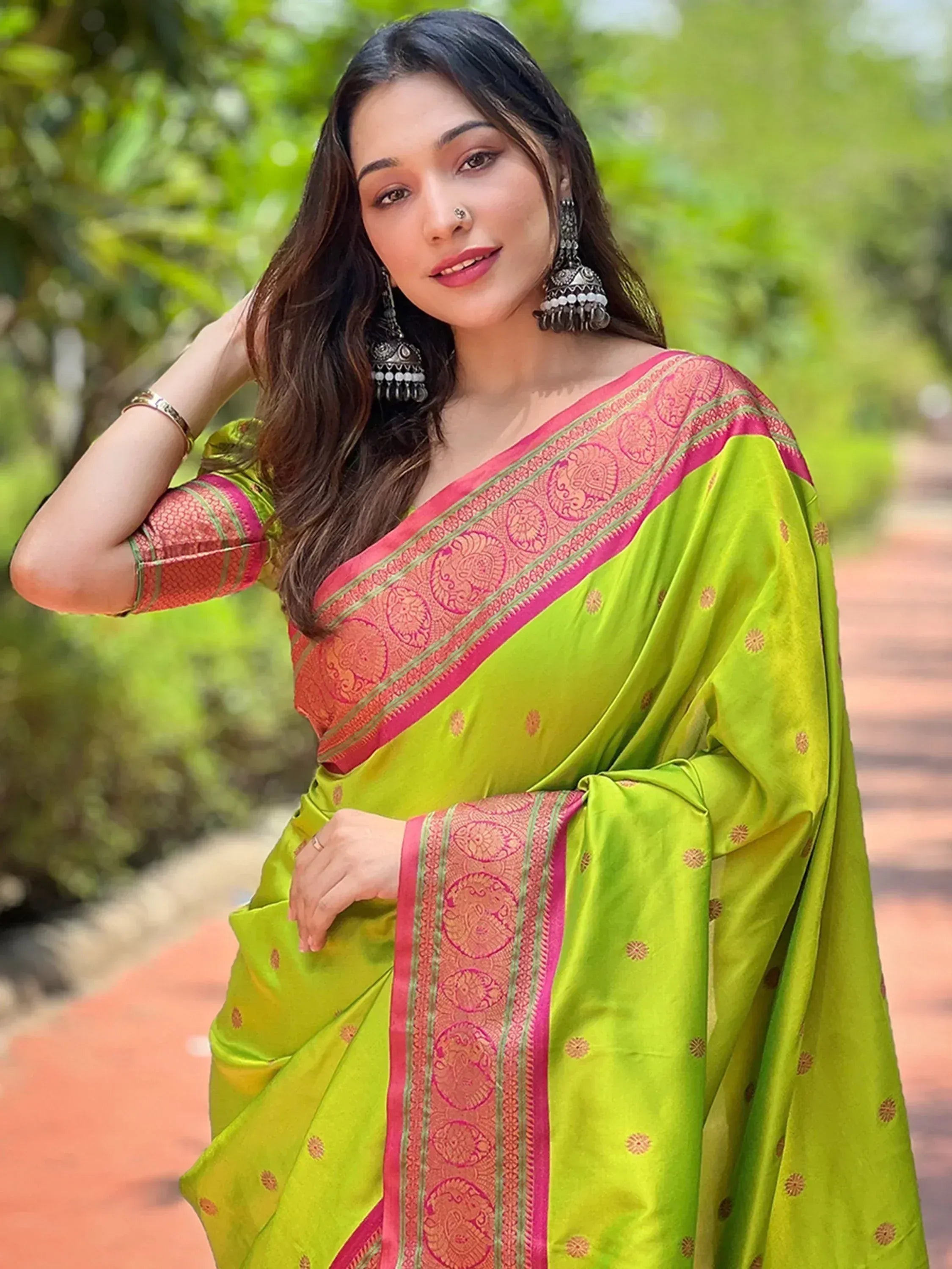 Vibrant green saree with pink border and gold motifs, styled with traditional earrings for ethnic wear