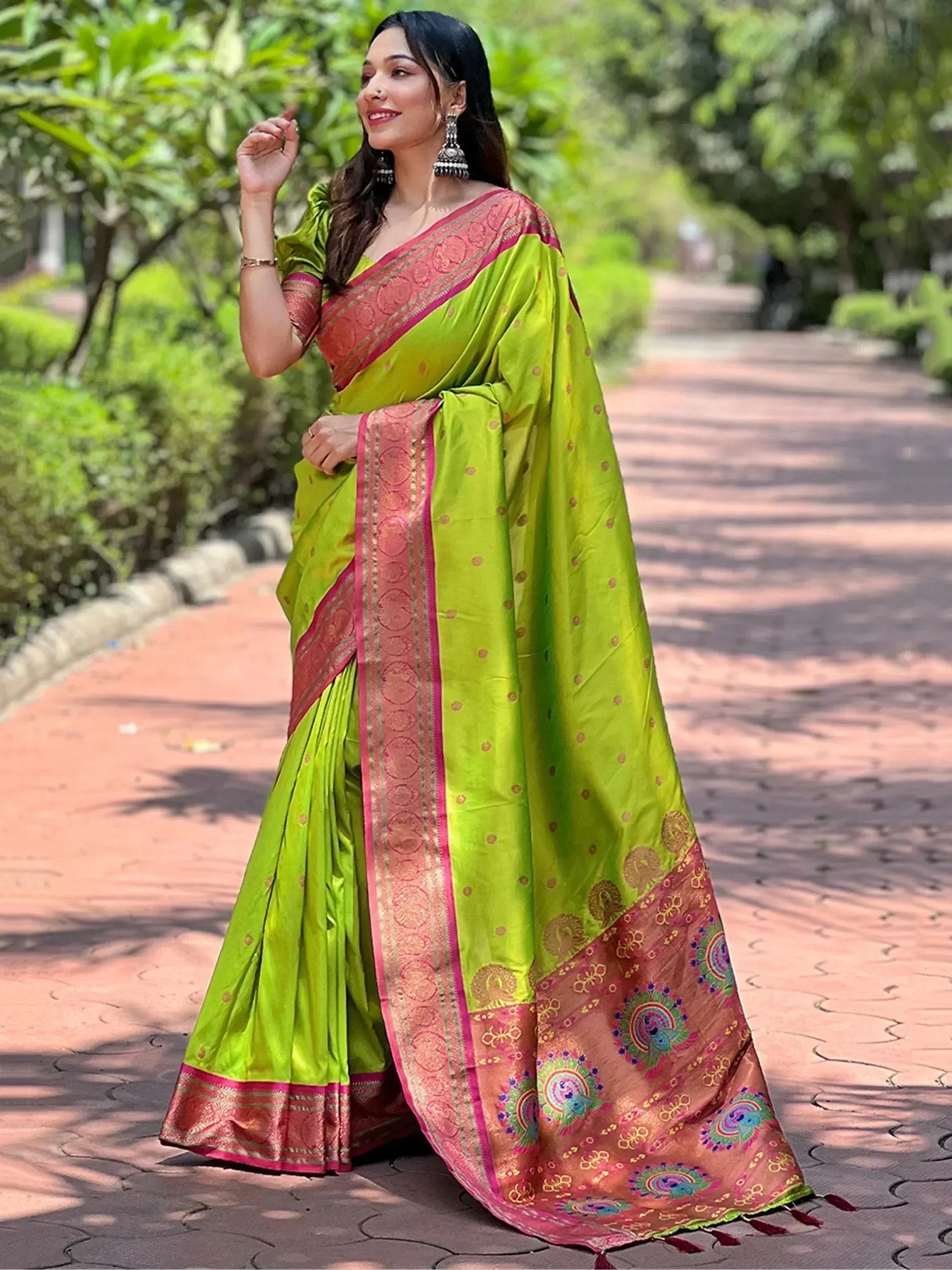 Woman in vibrant green saree with pink border and peacock motifs, styled for ethnic occasions