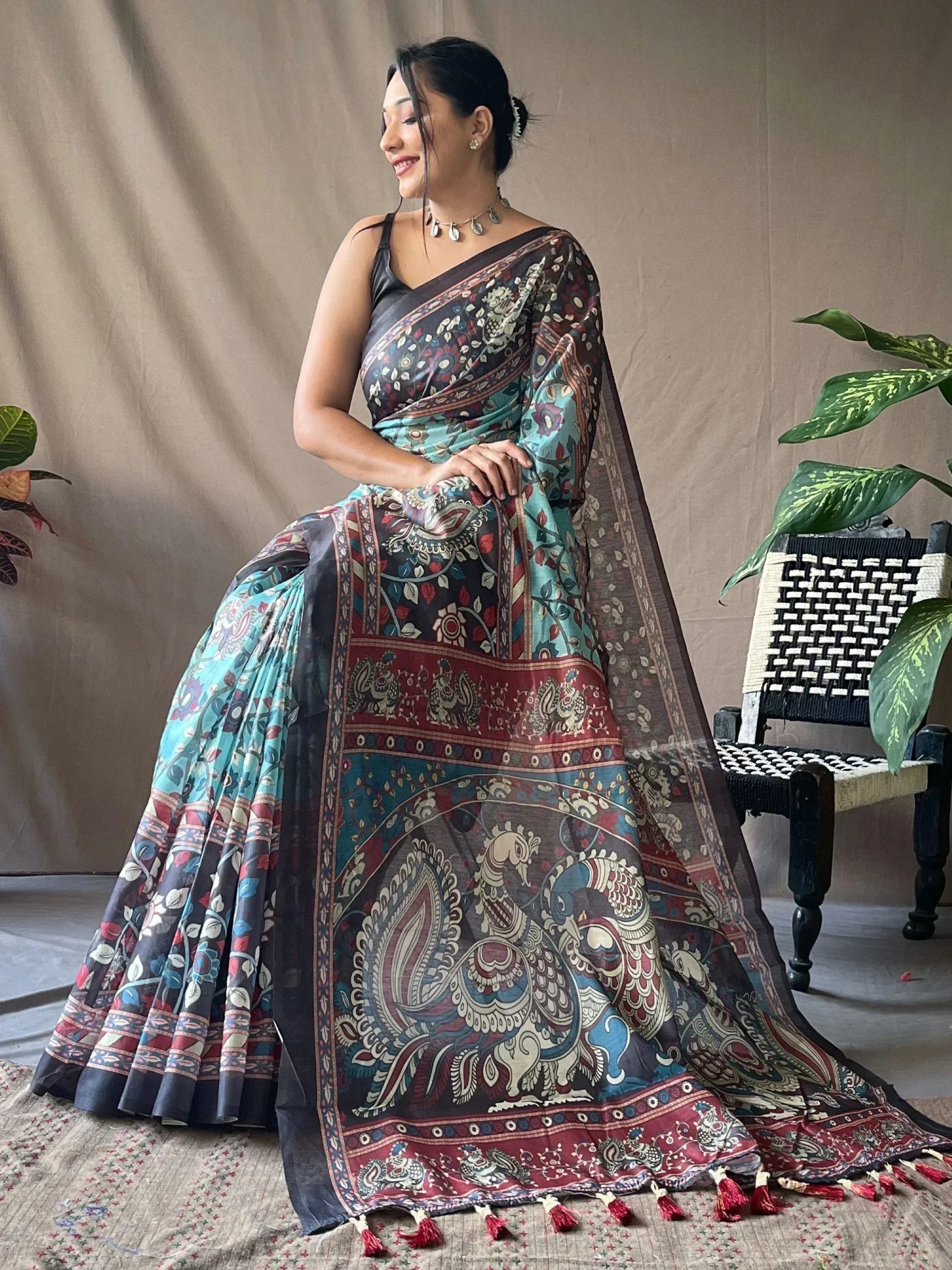 Woman in elegant Indian saree with peacock print, floral motifs, and tassels, styled for ethnic occasions.