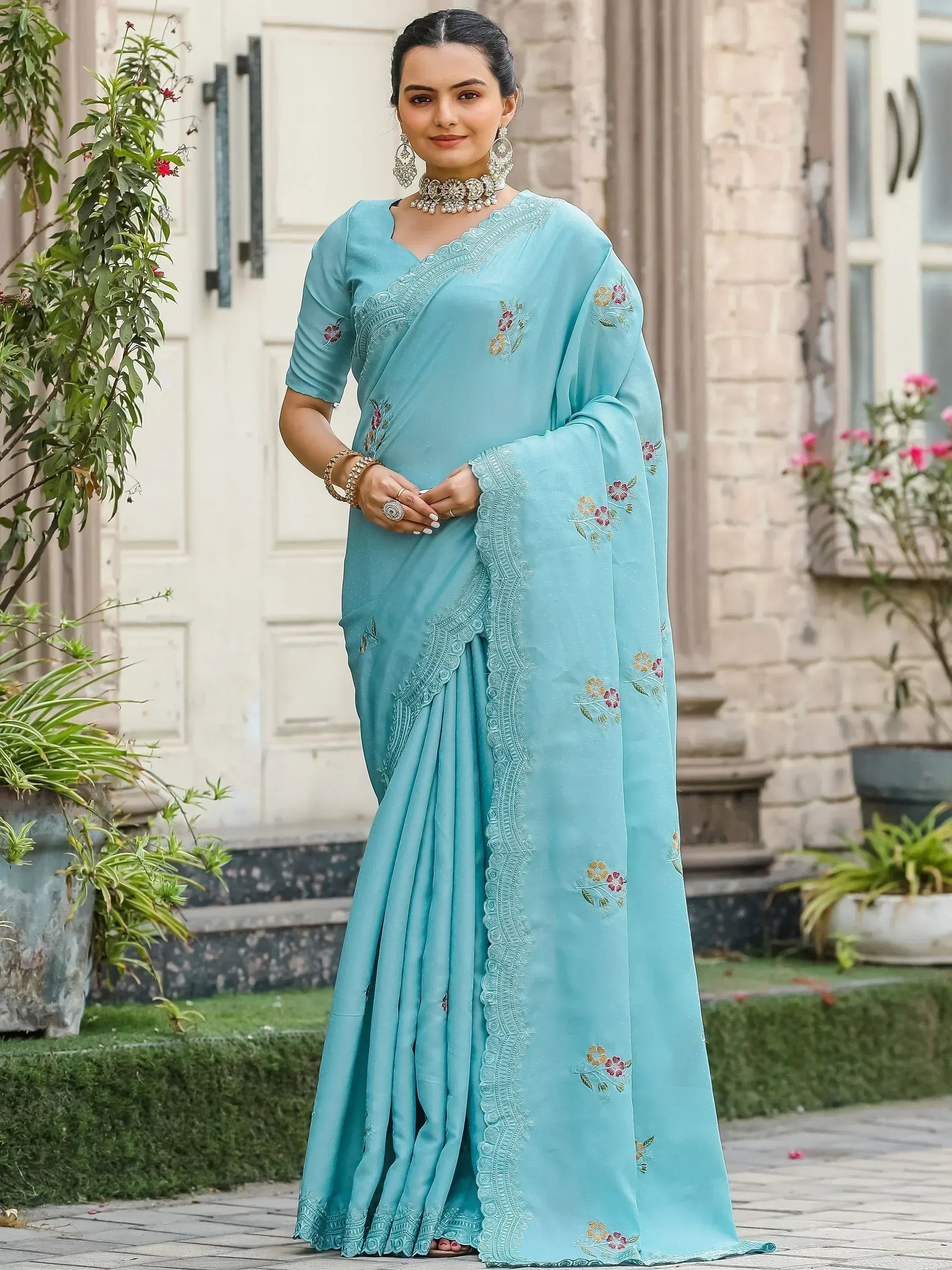 Light blue embroidered saree with floral motifs and lace border, styled with traditional jewelry for ethnic wear.