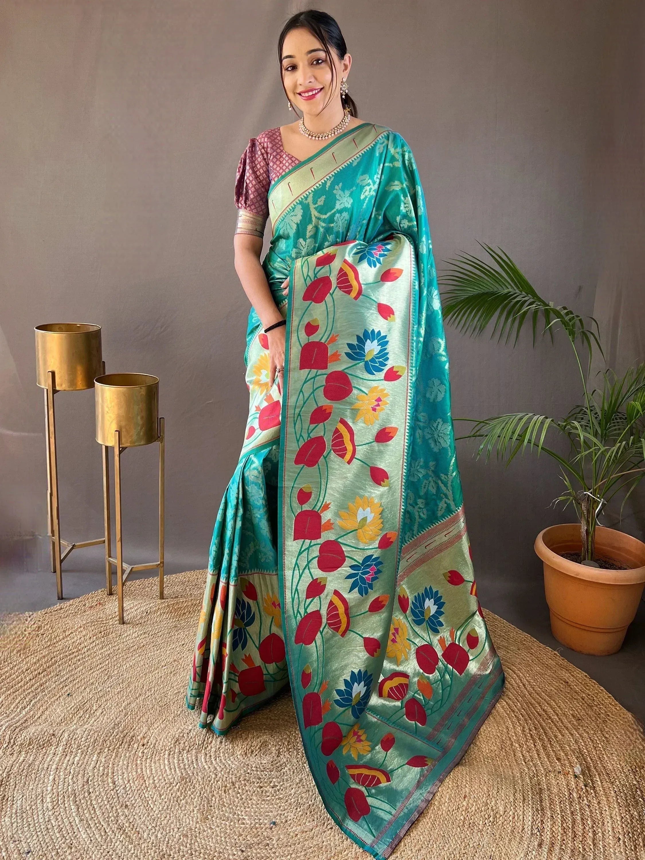 Woman in vibrant teal floral saree with colorful print, paired with pink blouse, perfect for ethnic occasions.