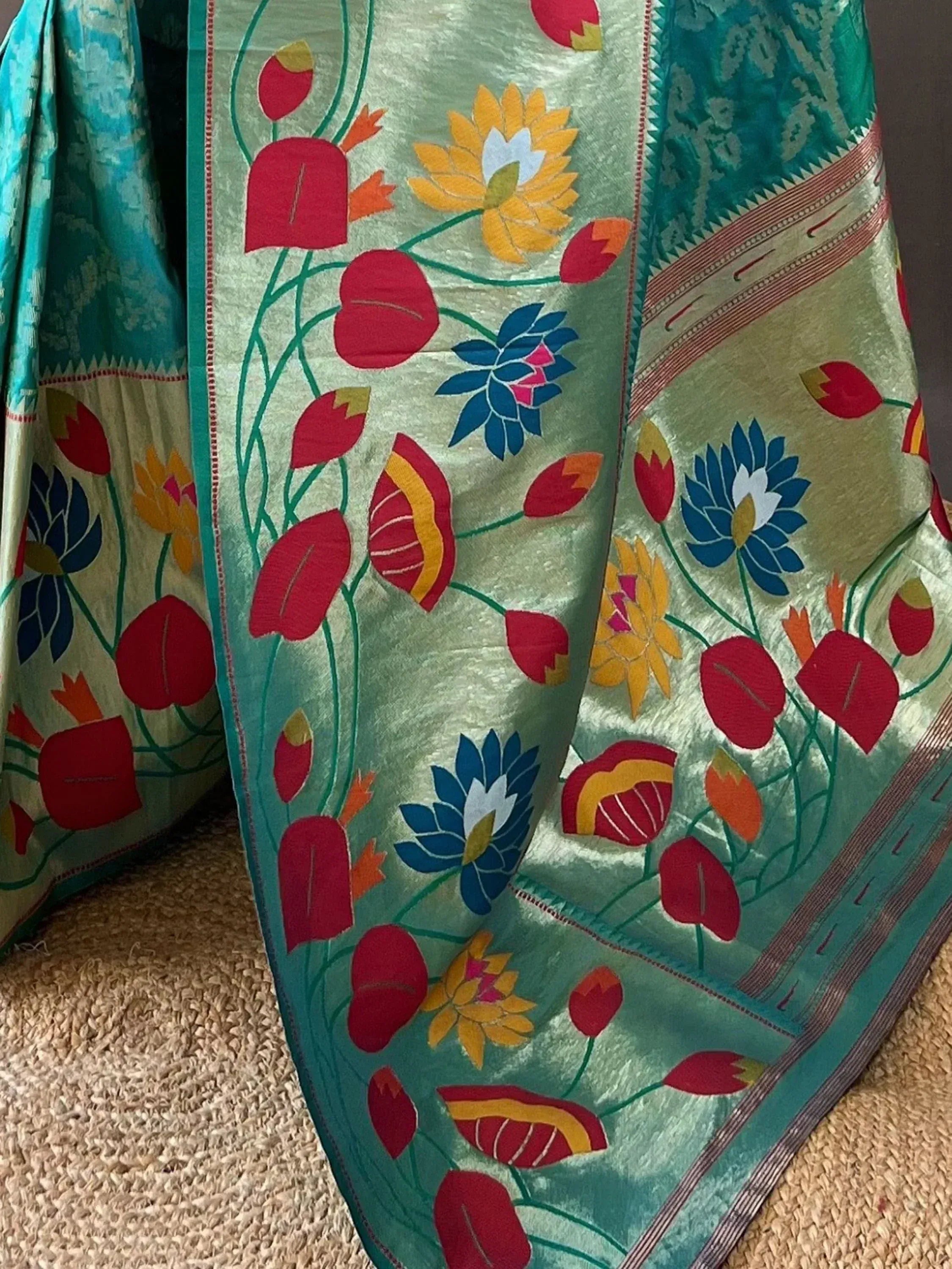 Vibrant floral printed saree with red, blue, and yellow lotus motifs on light green silk fabric