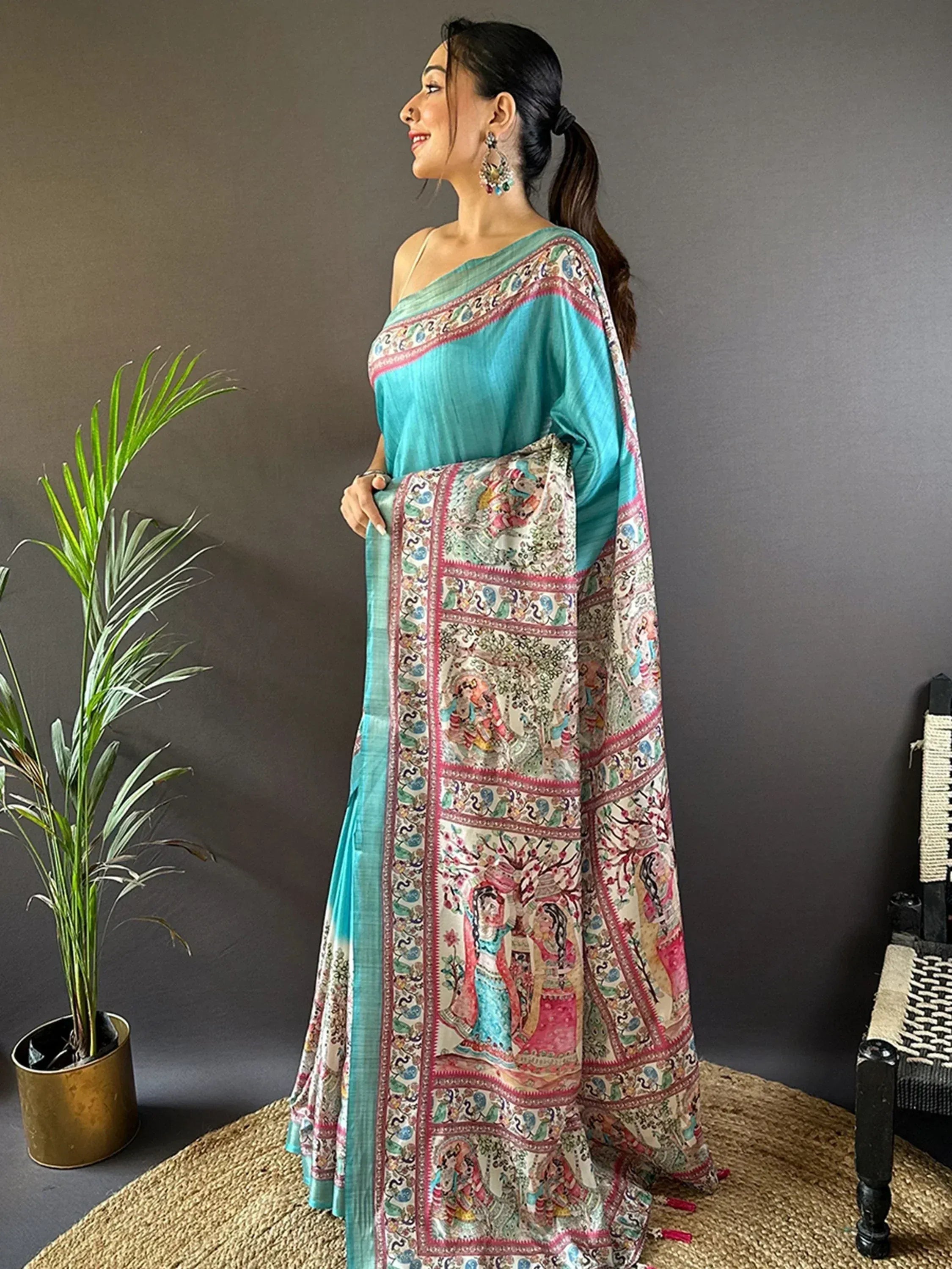 Woman in turquoise saree with intricate printed border, ethnic Indian wear